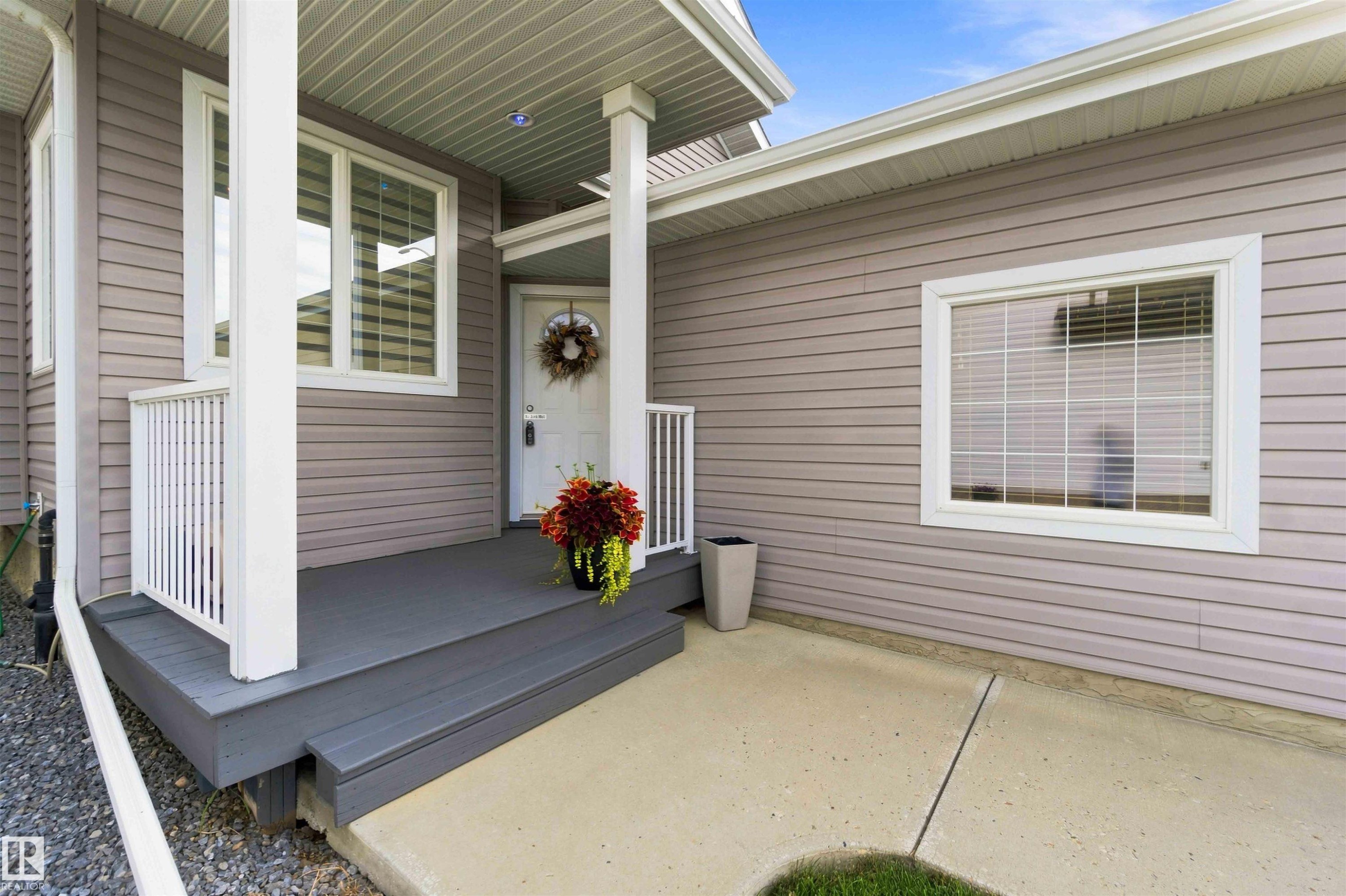 Front entry featuring a gray-painted porch with white railings, a white entry door, and light-toned horizontal siding - 6320 166 Avenue Nw, Edmonton, AB - Outdoor With Exterior