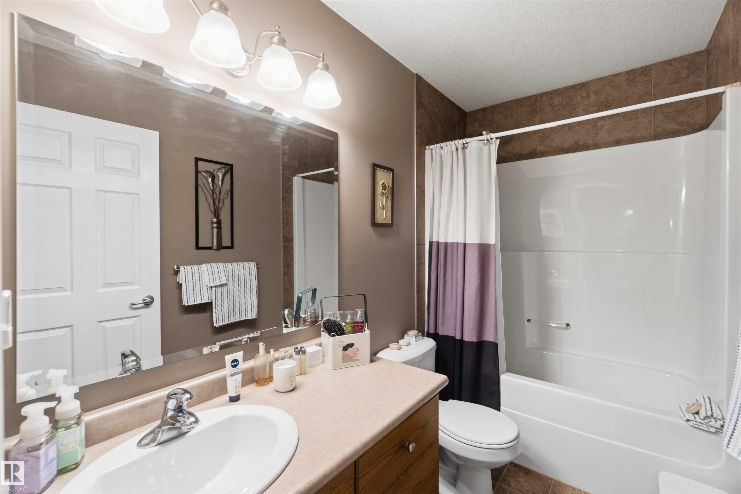 Bathroom featuring a single vanity with an integrated sink, polished chrome faucet, and a large wall-mounted mirror - 6320 166 Avenue Nw, Edmonton, AB - Indoor Photo Showing Bathroom