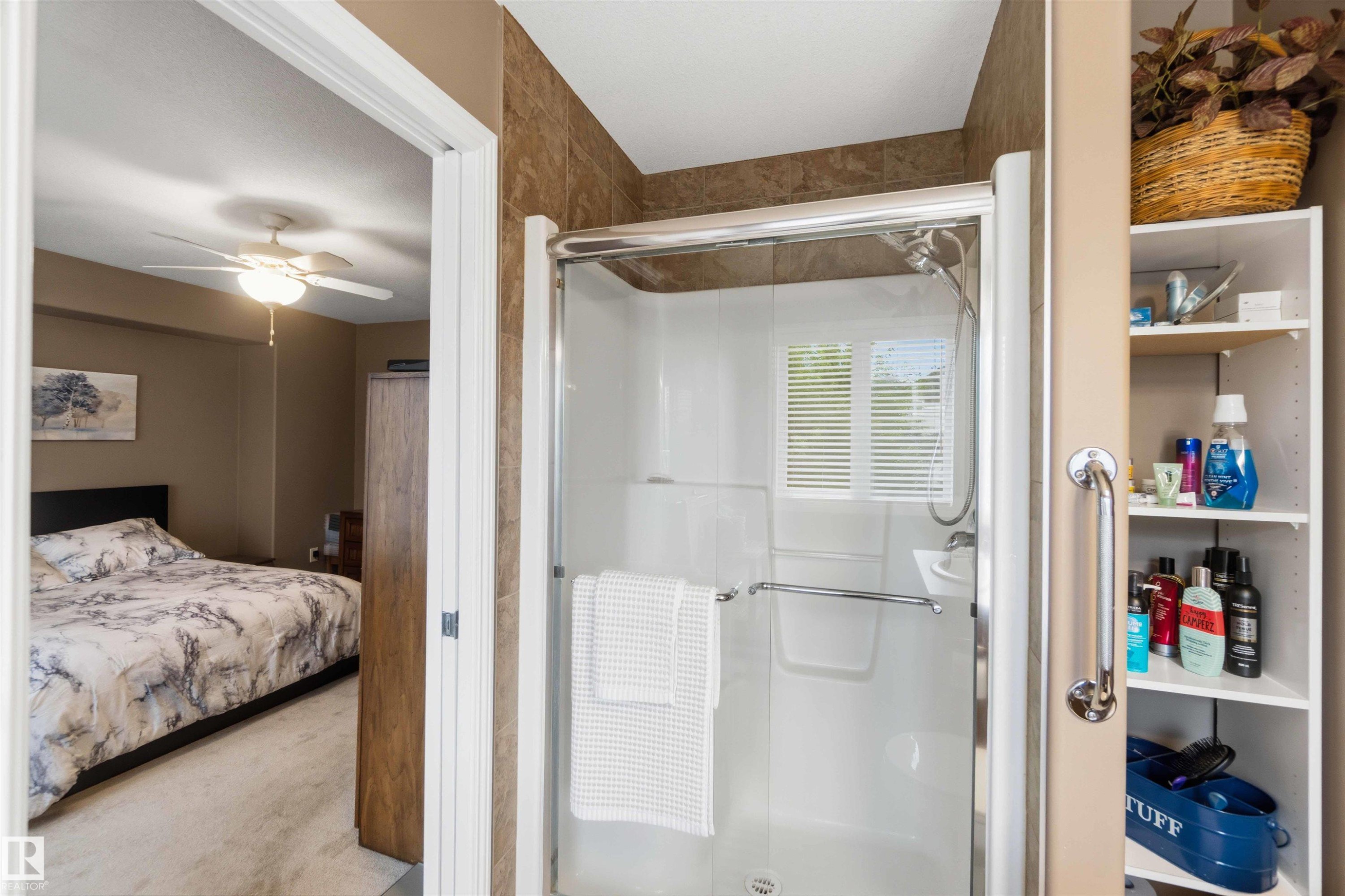 Shower enclosure featuring a clear glass door, chrome hardware, built-in shelving, and a window with blinds - 6320 166 Avenue Nw, Edmonton, AB - Indoor Photo Showing Bathroom