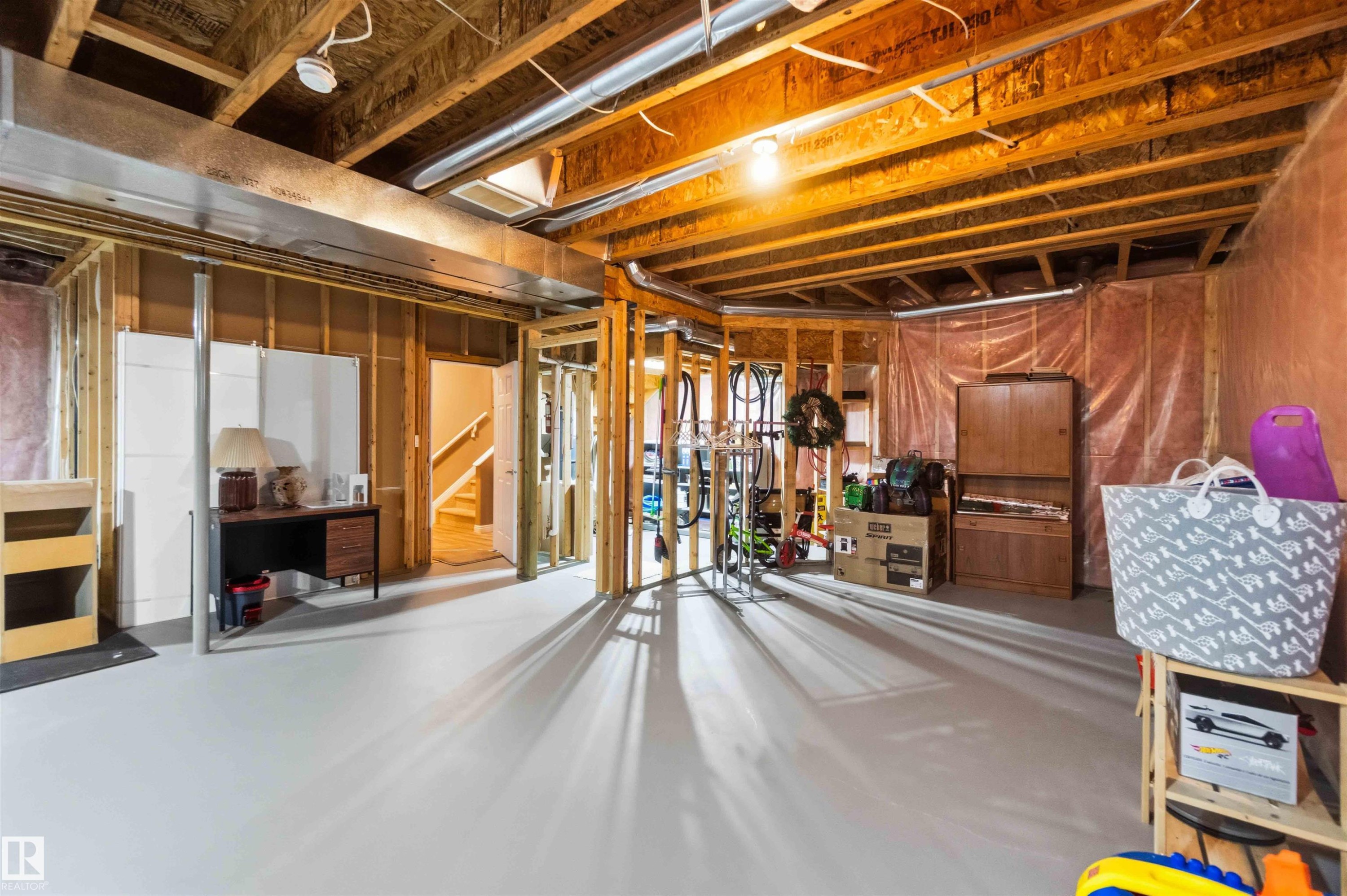 Unfinished basement featuring exposed wood framing, painted concrete flooring, and visible ductwork - 6320 166 Avenue Nw, Edmonton, AB - Indoor Photo Showing Basement