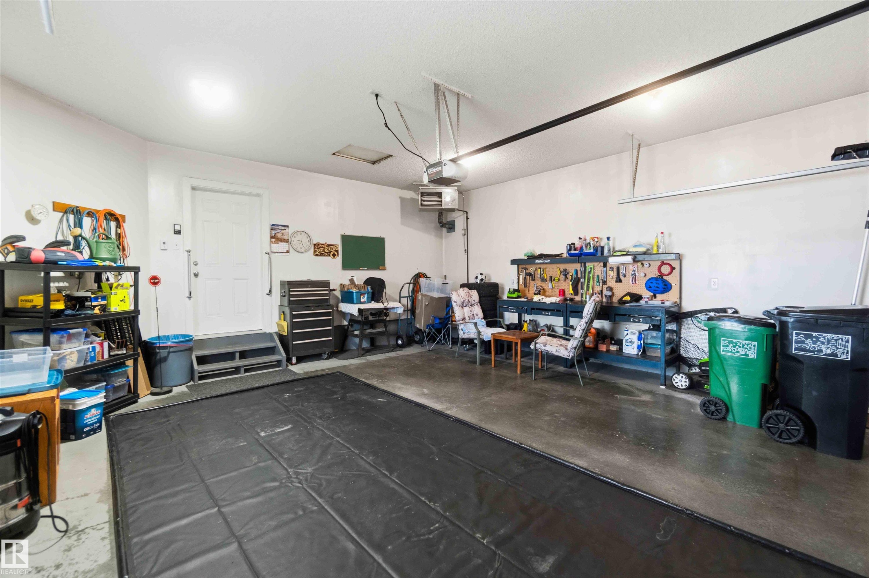 Spacious garage with concrete flooring, overhead lighting, an interior access door, and a built-in workbench - 6320 166 Avenue Nw, Edmonton, AB - Indoor Photo Showing Garage