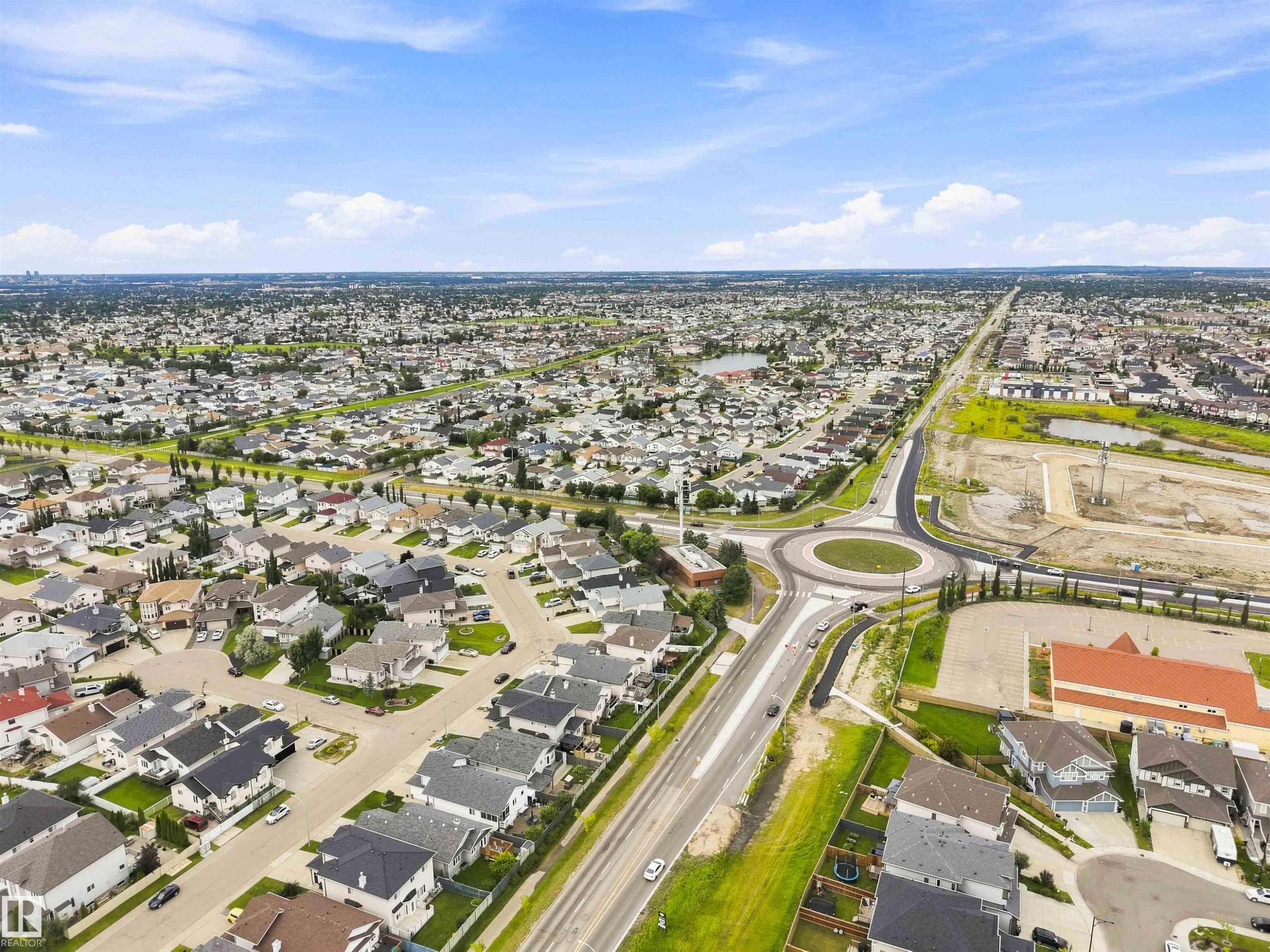 Expansive aerial landscape highlighting a developed residential area with numerous single-family homes and a prominent roundabout - 6320 166 Avenue Nw, Edmonton, AB - Outdoor With View