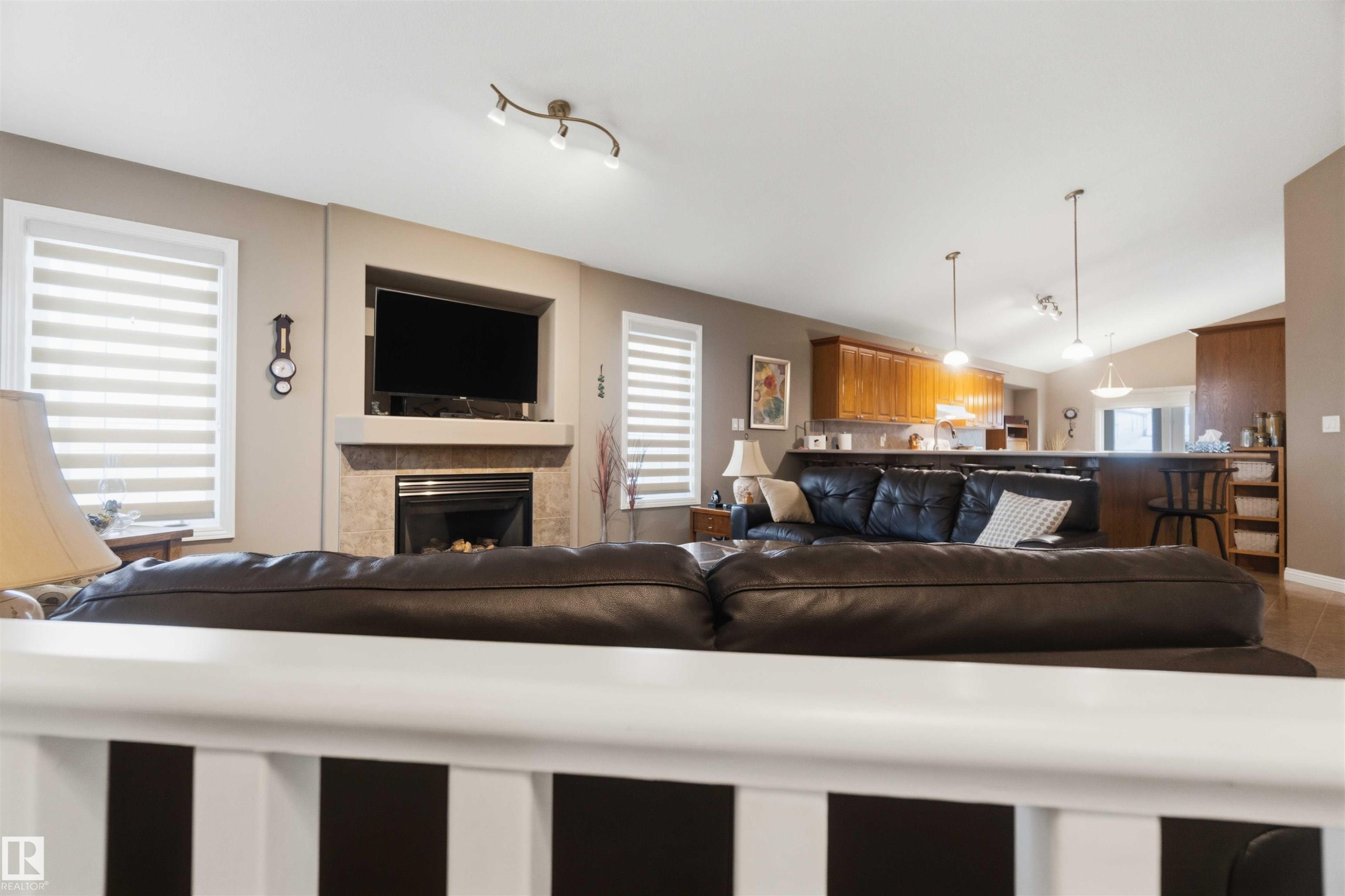 Living area featuring a fireplace with a stone surround, integrated television niche, and track lighting - 6320 166 Avenue Nw, Edmonton, AB - Indoor Photo Showing Living Room With Fireplace