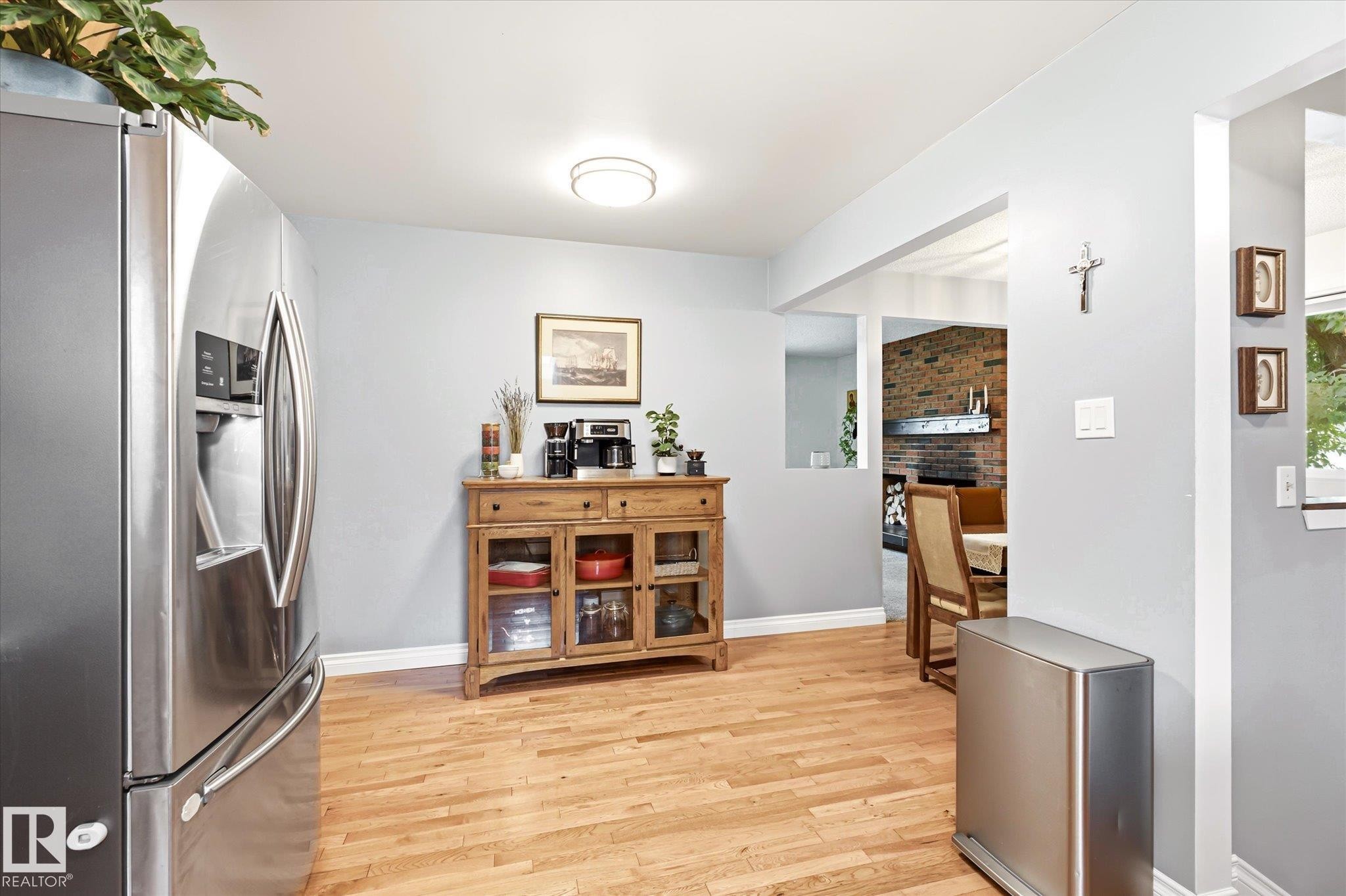 Expansive wood-finish flooring throughout, complemented by light gray wall tones and white baseboards - 4921 47 Avenue, Legal, AB - Indoor