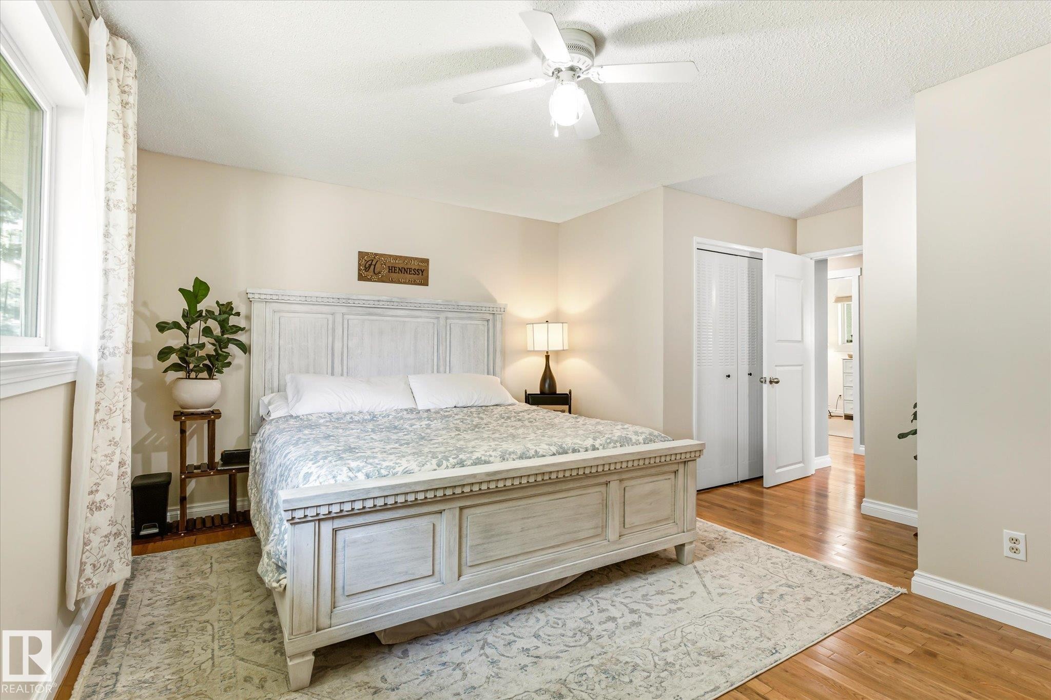 Bedroom featuring a ceiling fan, hardwood flooring, and a window with white trim - 4921 47 Avenue, Legal, AB - Indoor Photo Showing Bedroom