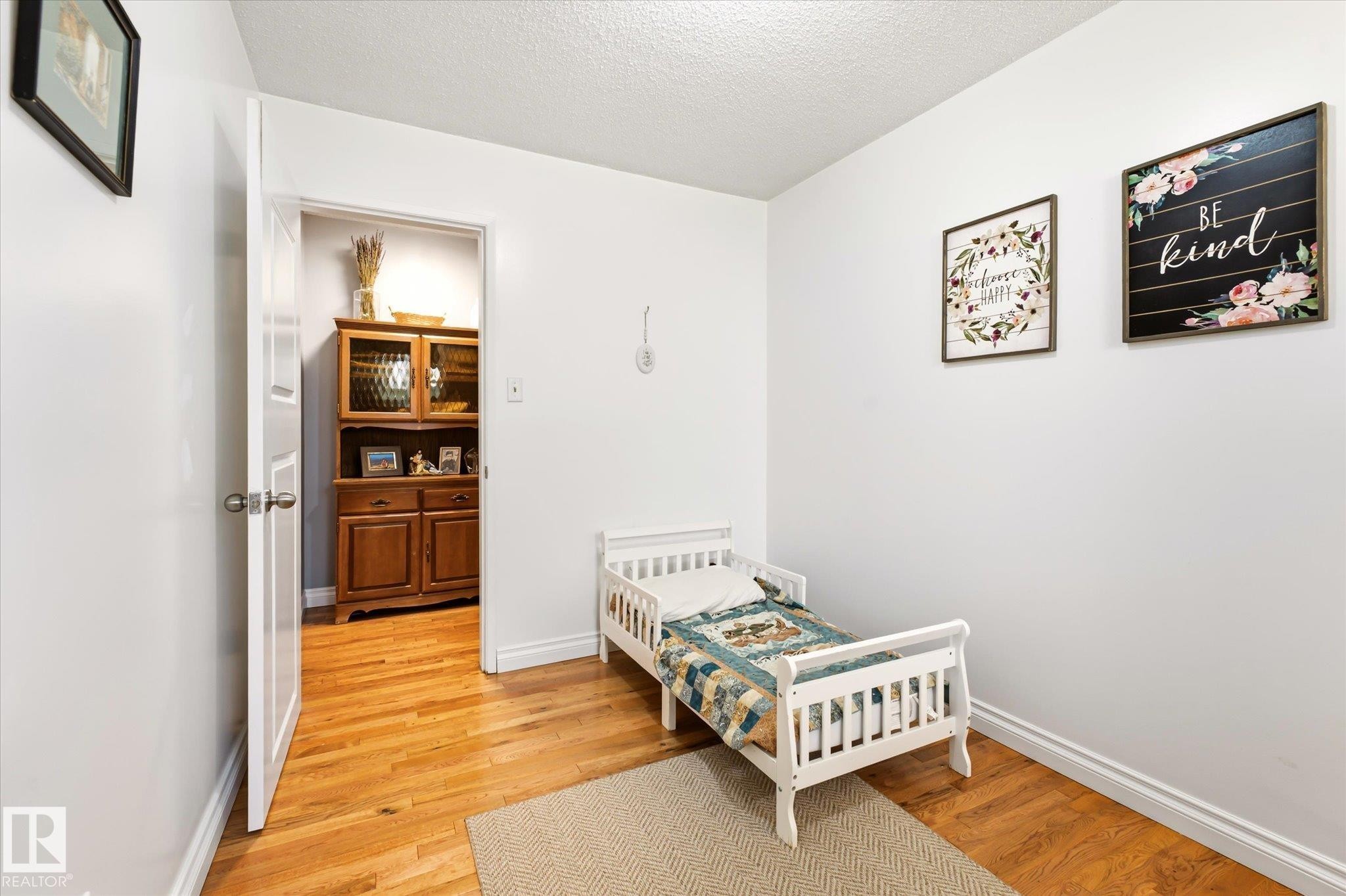 Hardwood flooring present in room and visible through doorway - 4921 47 Avenue, Legal, AB - Indoor Photo Showing Bedroom