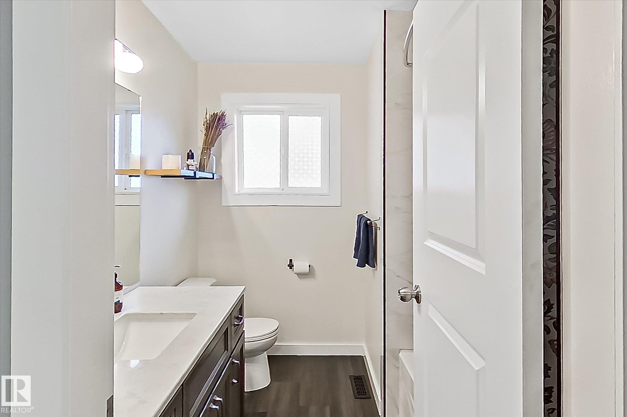 Bathroom featuring a dark wood-finish vanity with an integrated sink, white countertop, and contemporary hardware - 4921 47 Avenue, Legal, AB - Indoor Photo Showing Bathroom