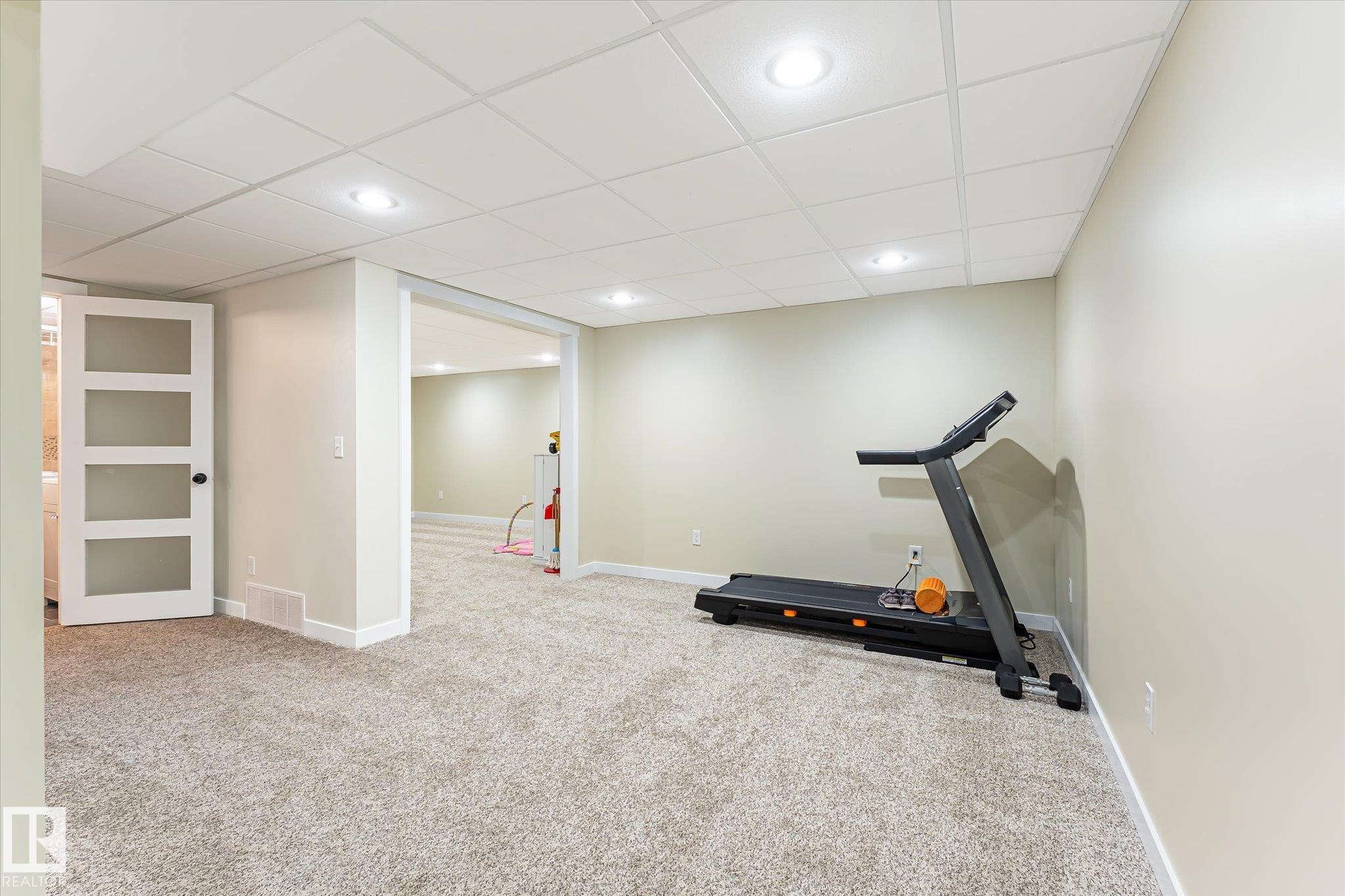 Spacious carpeted room featuring recessed lighting, a drop ceiling, and light-toned walls - 4921 47 Avenue, Legal, AB - Indoor Photo Showing Gym Room