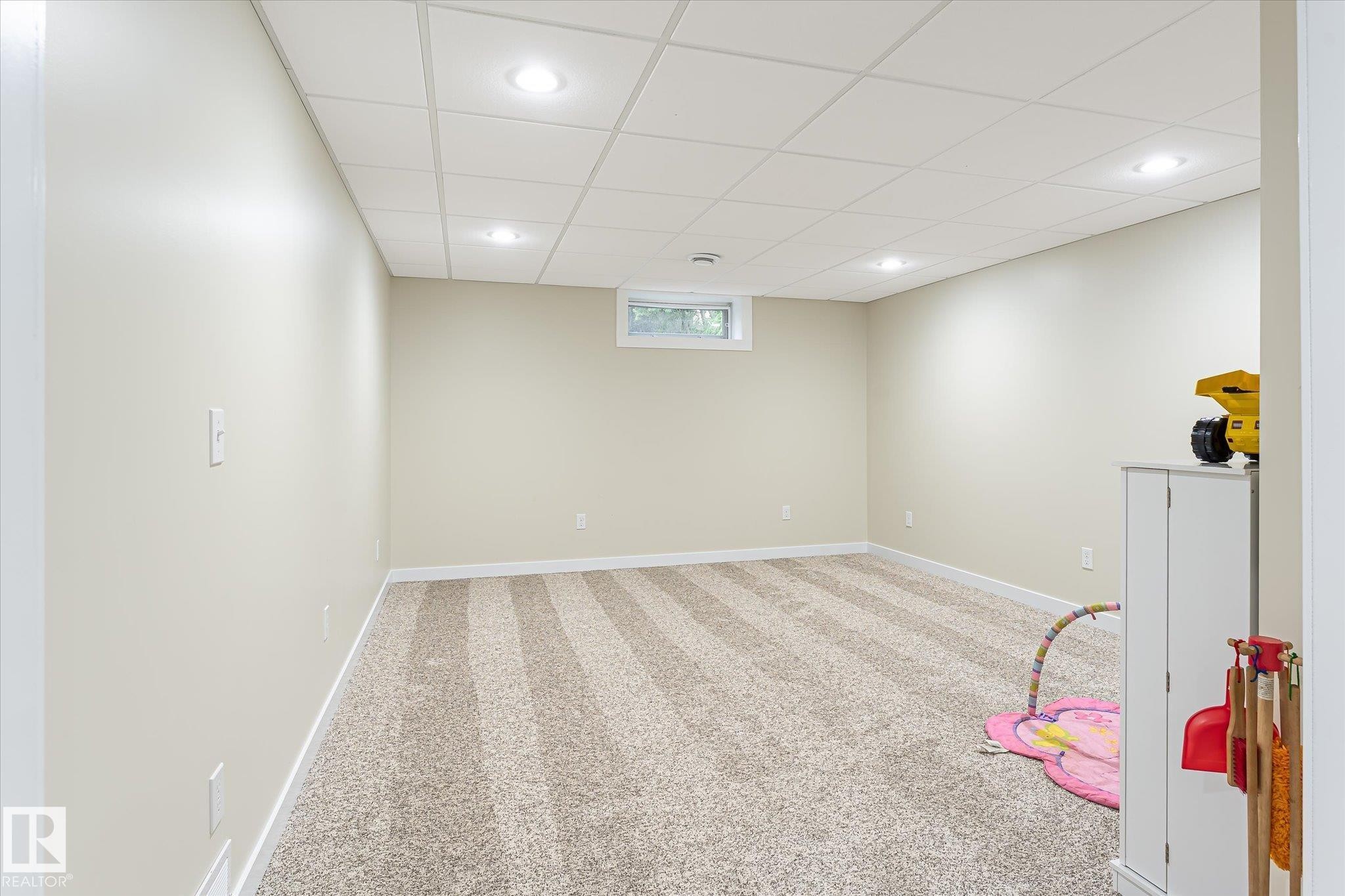 Finished room with light-toned walls and striped carpeting - 4921 47 Avenue, Legal, AB - Indoor Photo Showing Basement