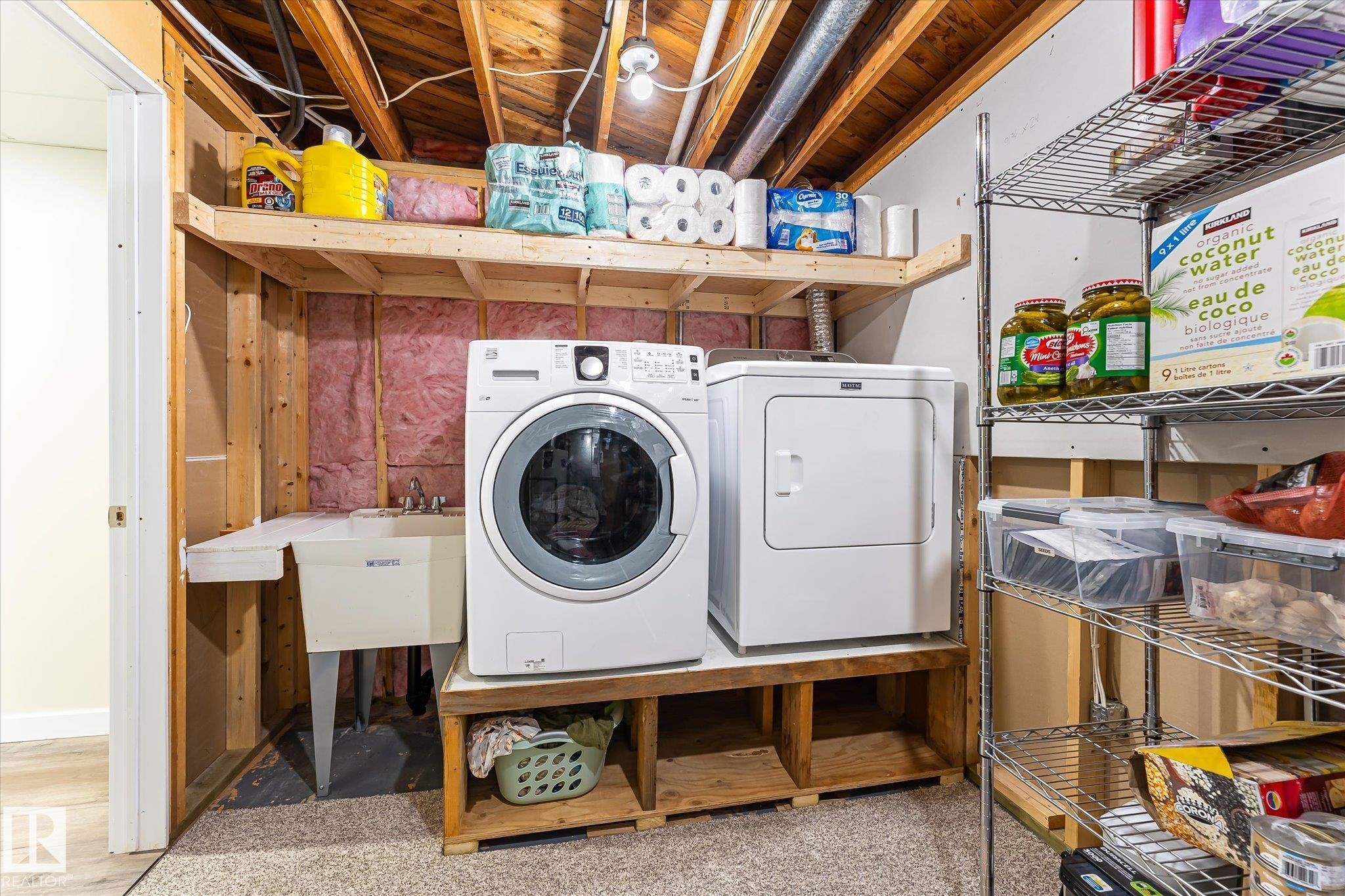 Dedicated laundry area featuring a front-load washer and dryer, utility sink, and overhead shelving - 4921 47 Avenue, Legal, AB - Indoor Photo Showing Laundry Room