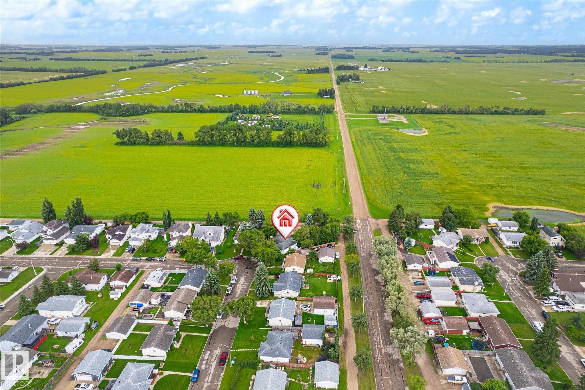 Aerial perspective showcasing a residential area bordered by expansive green fields - 4921 47 Avenue, Legal, AB - Outdoor With View