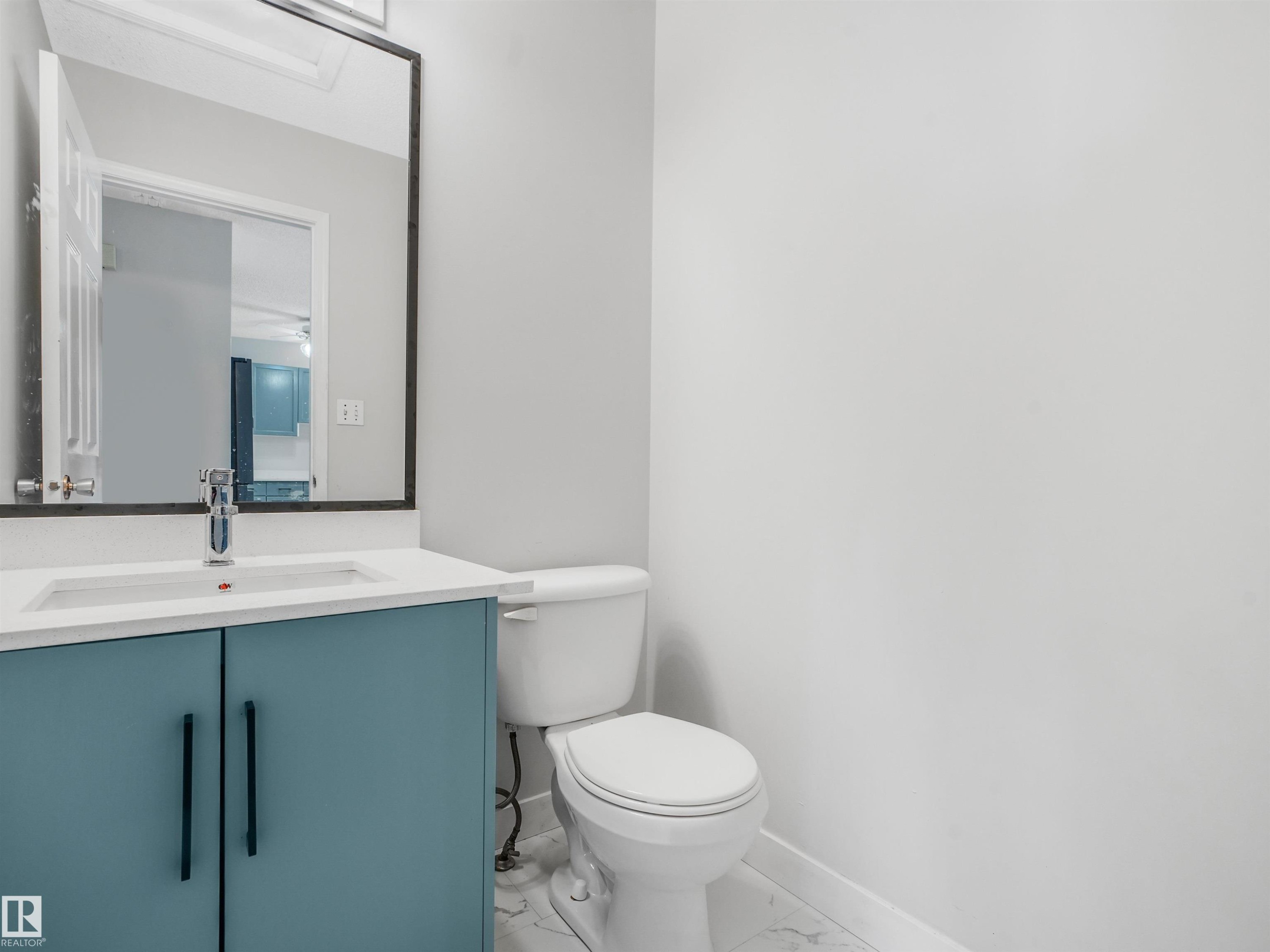 Powder room featuring a blue vanity with a white countertop, modern sink, and chrome faucet - #2 3311 58 St Nw, Edmonton, AB - Indoor Photo Showing Bathroom