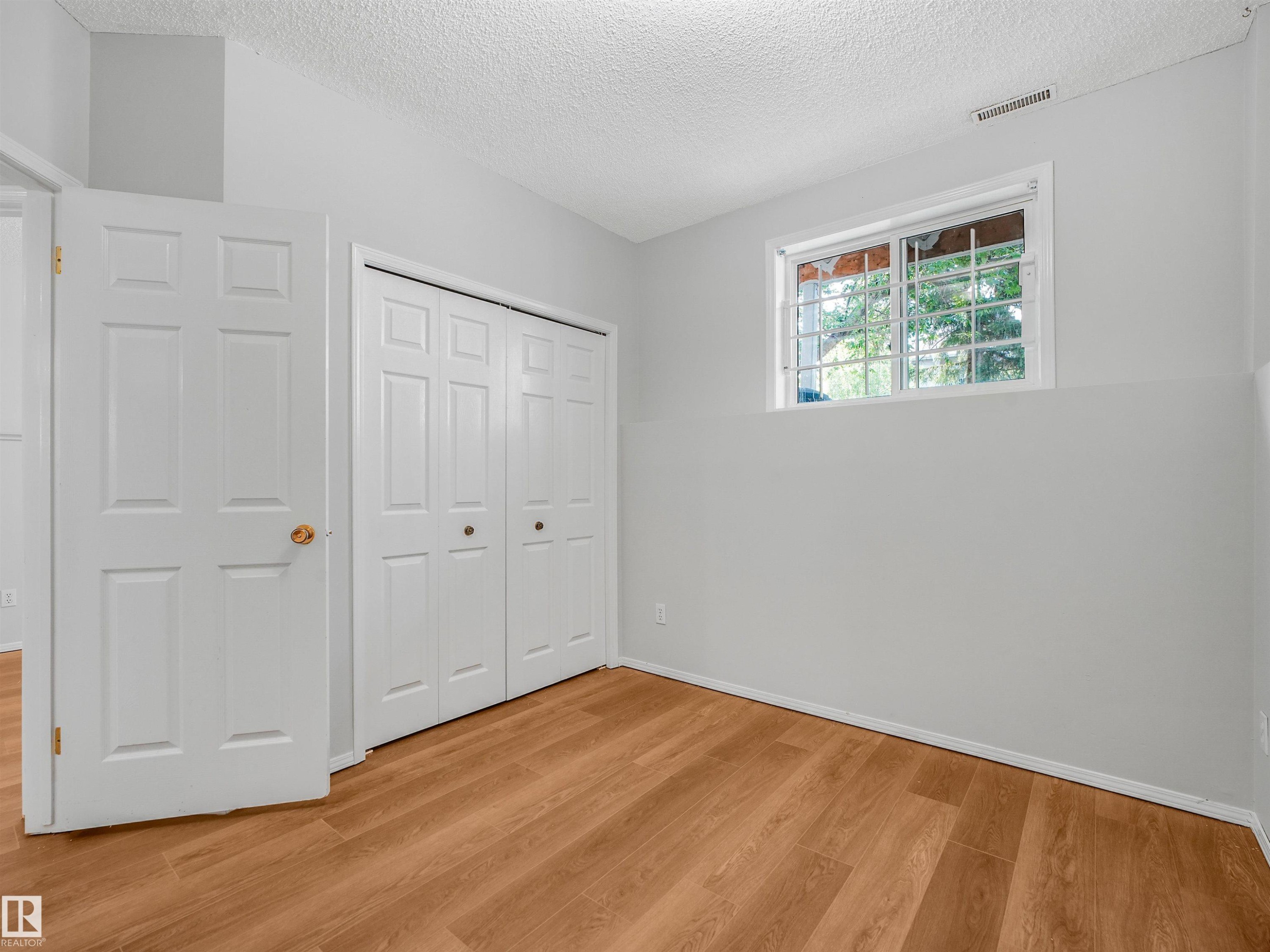 Room featuring wood-finish flooring, white walls, and a white bi-fold closet - #2 3311 58 St Nw, Edmonton, AB - Indoor Photo Showing Other Room