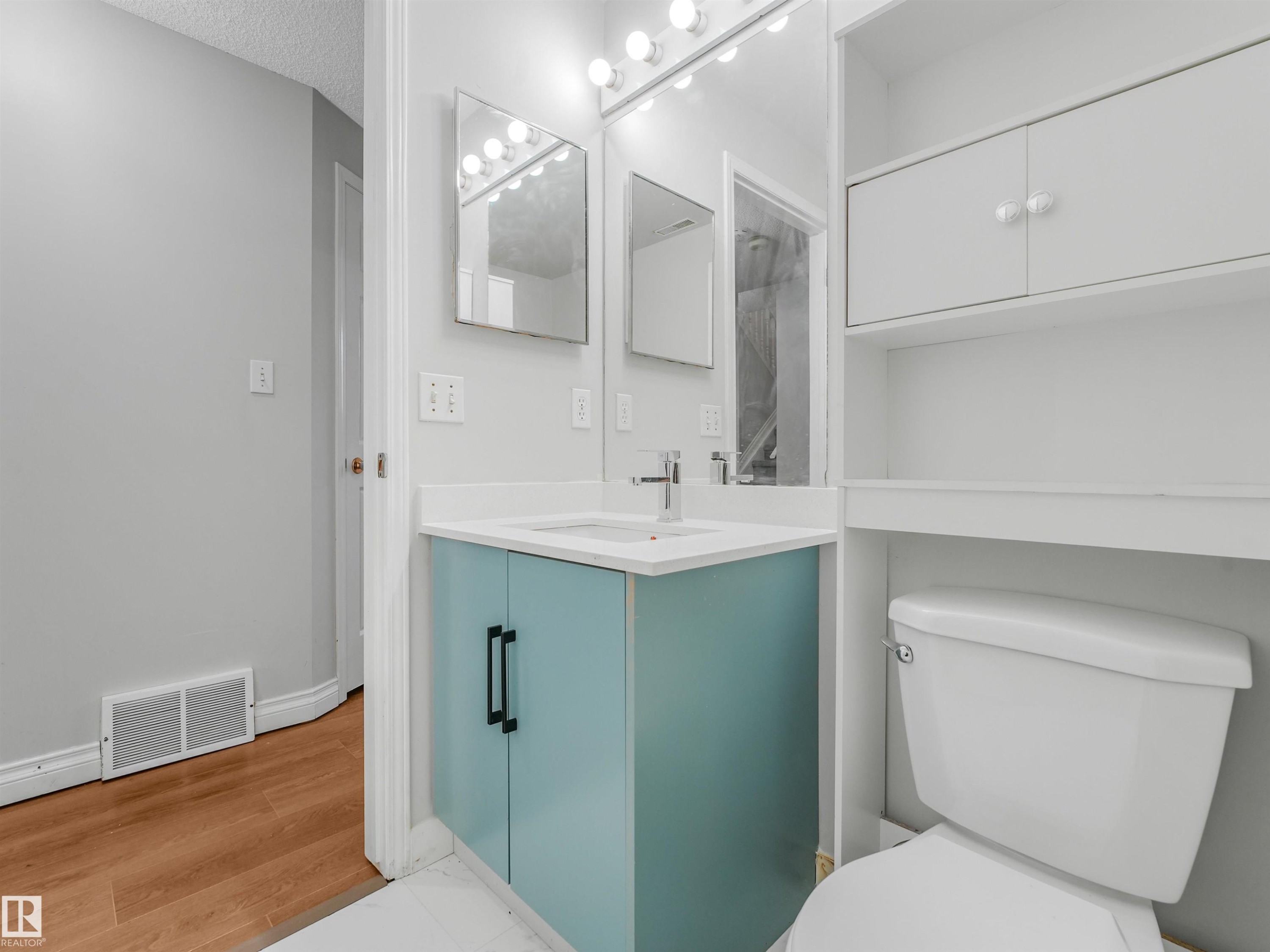 Bathroom vanity featuring a light blue cabinet with black hardware, a white countertop, and a rectangular undermount sink - #2 3311 58 St Nw, Edmonton, AB - Indoor Photo Showing Bathroom