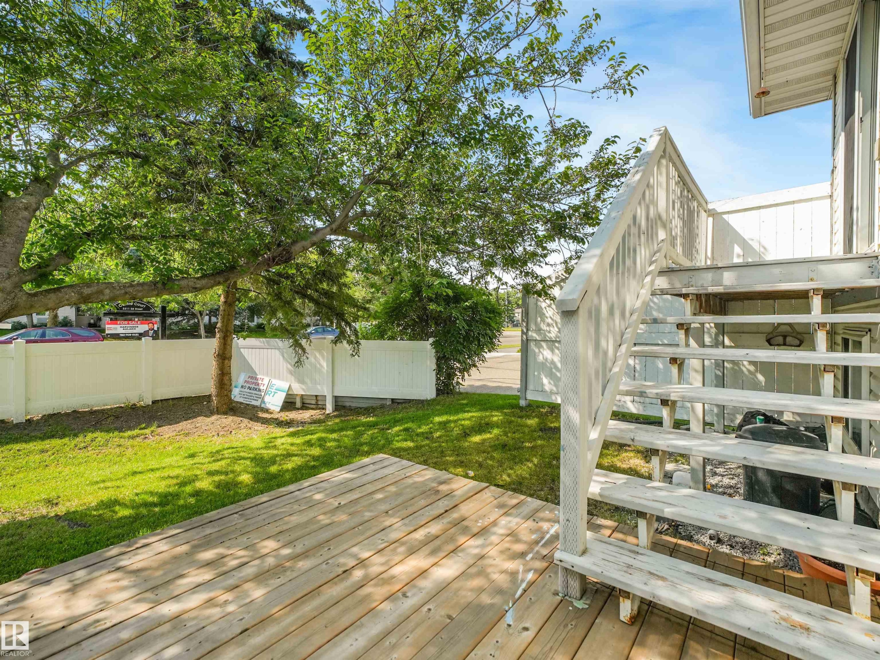 Rear wood-finish deck with wooden steps, surrounded by a green lawn and mature trees - #2 3311 58 St Nw, Edmonton, AB - Outdoor With Deck Patio Veranda