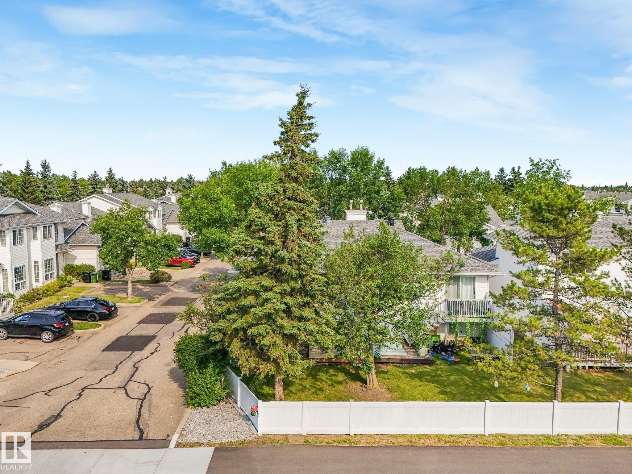 Townhome community featuring white exterior finishes, gray shingle roofs, and mature landscaping - #2 3311 58 St Nw, Edmonton, AB - Outdoor