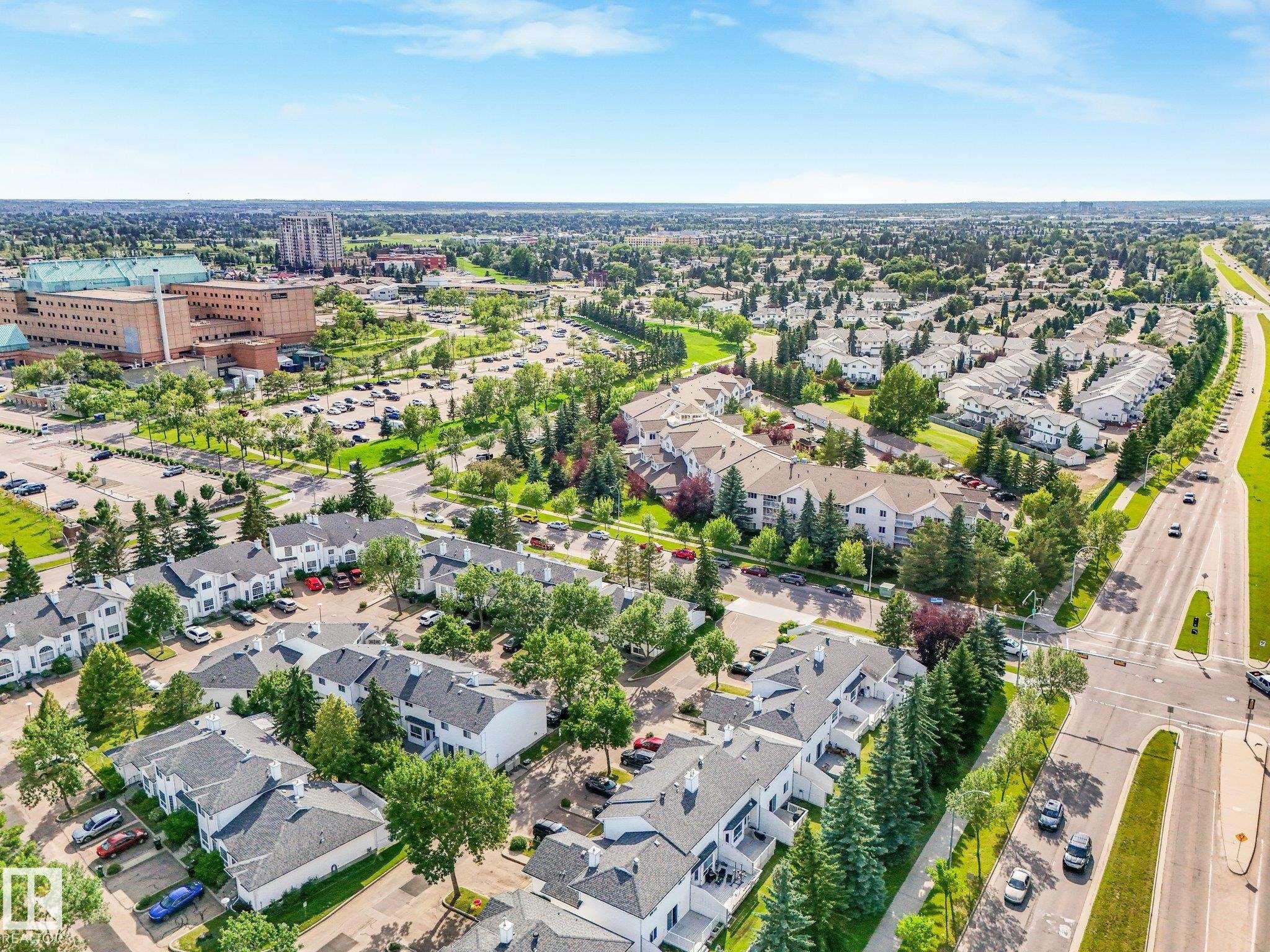 Expansive residential area featuring a mix of townhomes and multi-story apartment buildings, bordered by mature trees and manicured green spaces - #2 3311 58 St Nw, Edmonton, AB - Outdoor With View