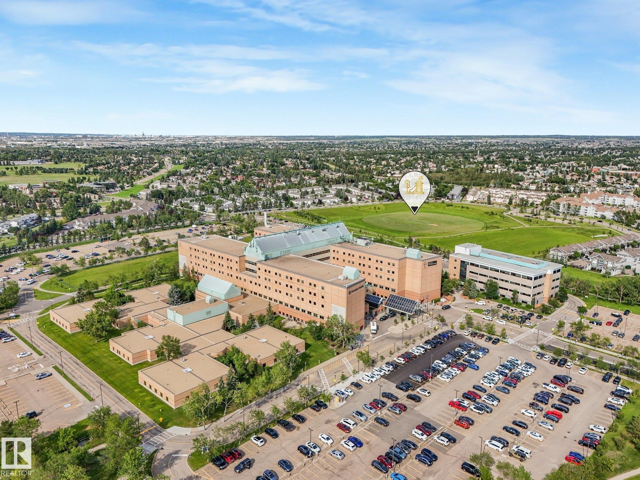 Large institutional building with expansive paved parking areas and surrounding green spaces - #2 3311 58 St Nw, Edmonton, AB - Outdoor With View