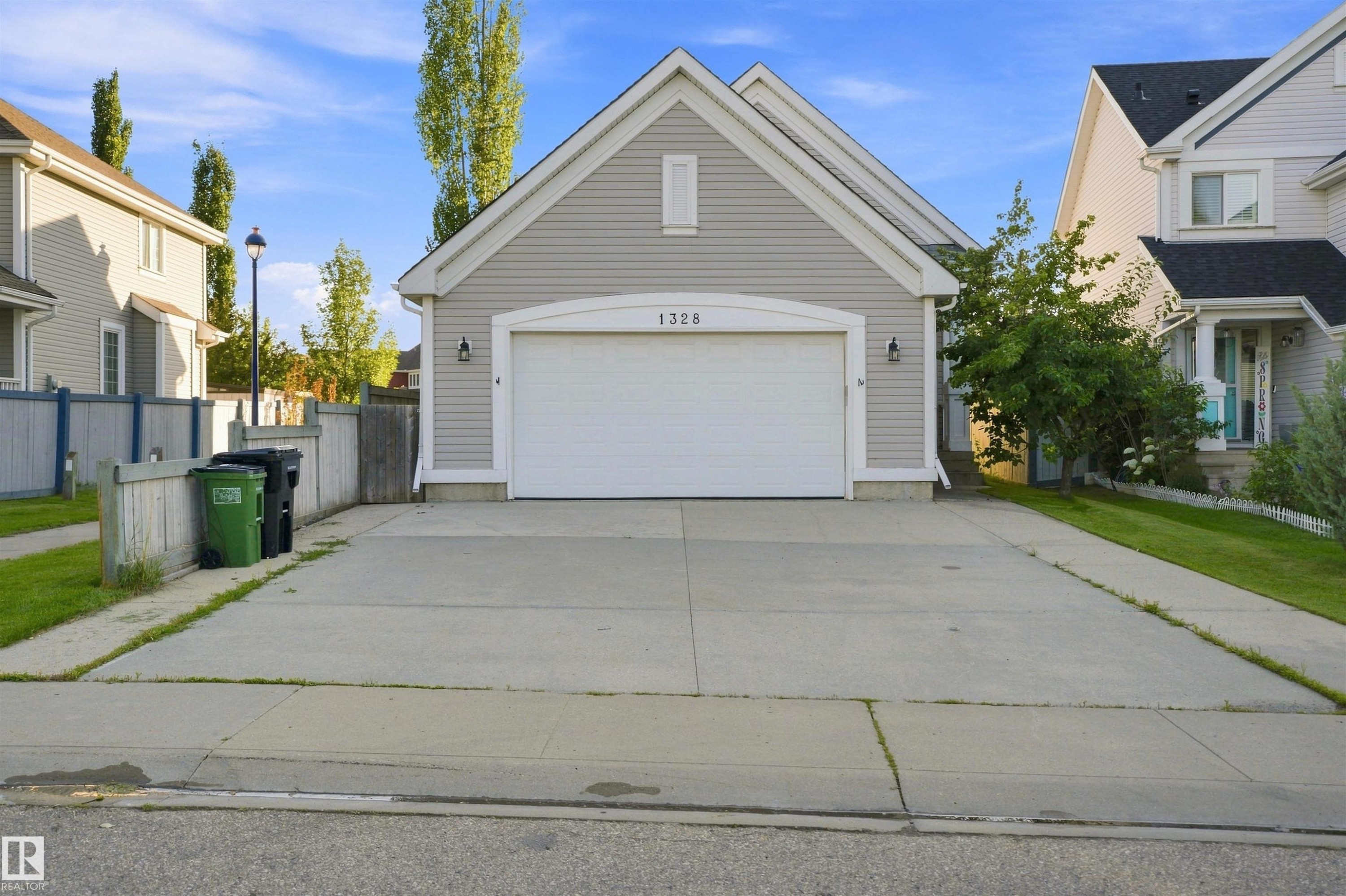 Light gray siding exterior with a white garage door featuring an arched transom - 1328 80 Street Sw, Edmonton, AB - Outdoor