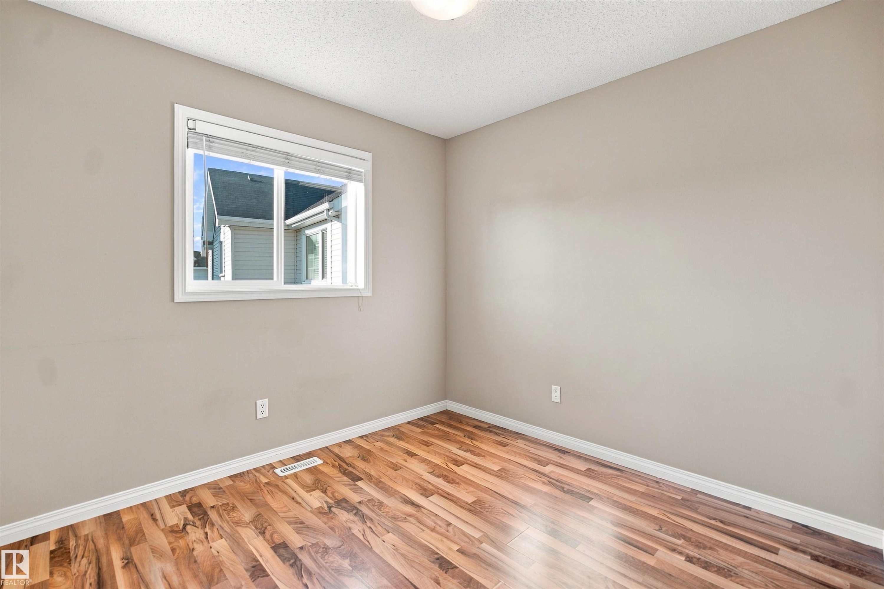 Hardwood-finish flooring complementing light neutral wall tones - 1328 80 Street Sw, Edmonton, AB - Indoor Photo Showing Other Room