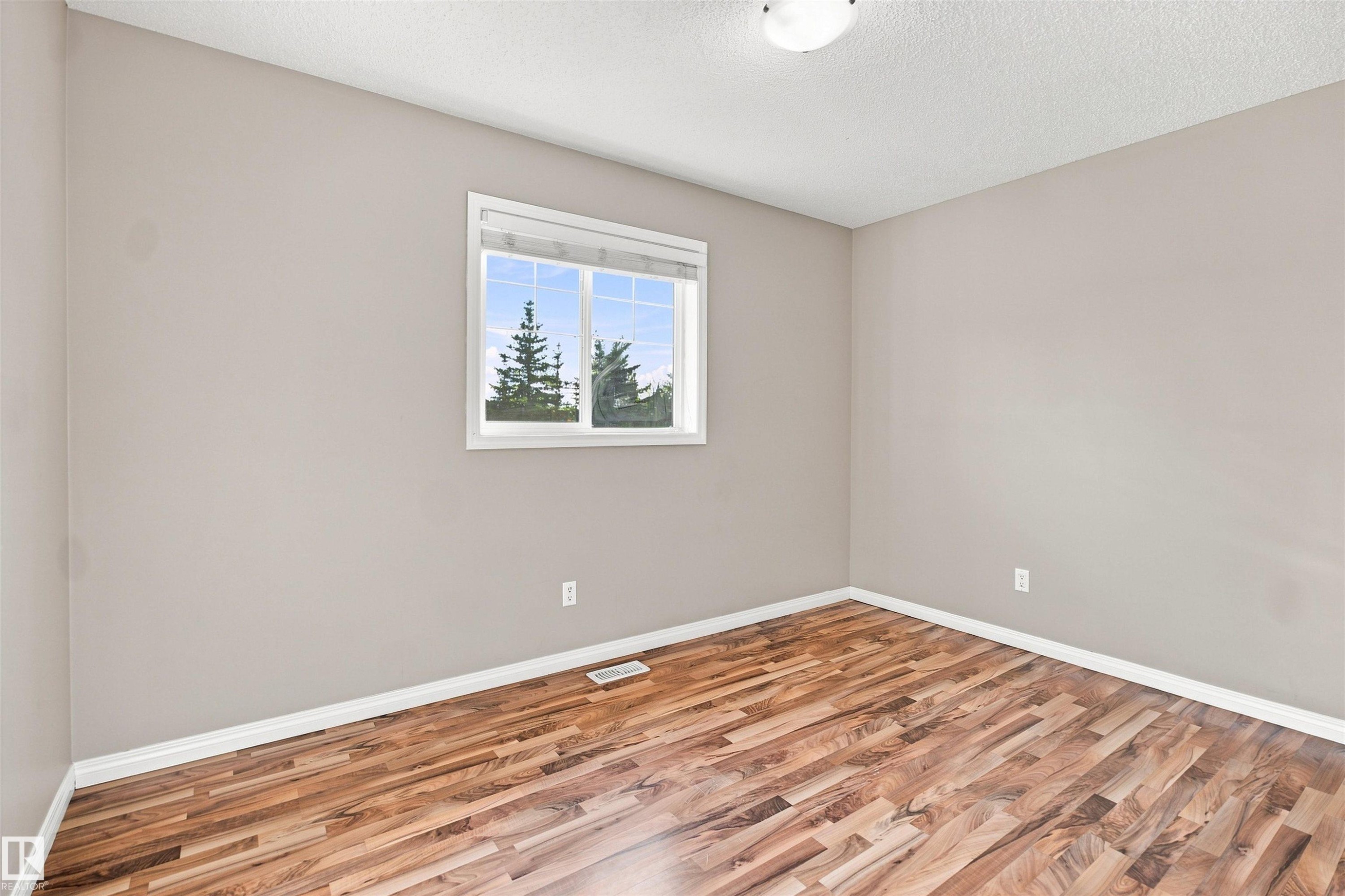 Interior room featuring wood-finish flooring, light neutral-toned walls, and white trim - 1328 80 Street Sw, Edmonton, AB - Indoor Photo Showing Other Room