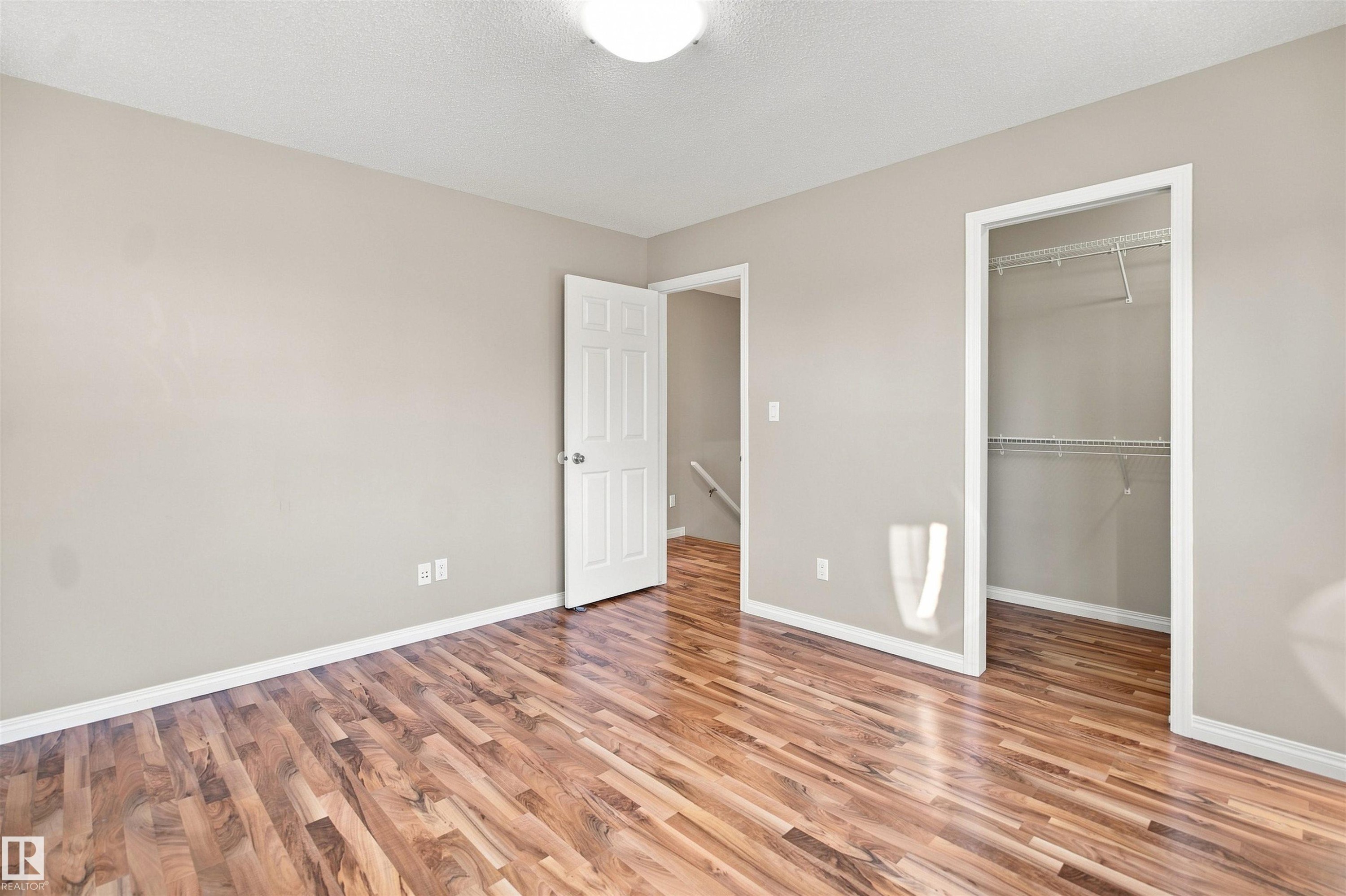 Room featuring wood-finish flooring, neutral wall tones, white trim, and a ceiling-mounted light fixture - 1328 80 Street Sw, Edmonton, AB - Indoor Photo Showing Other Room