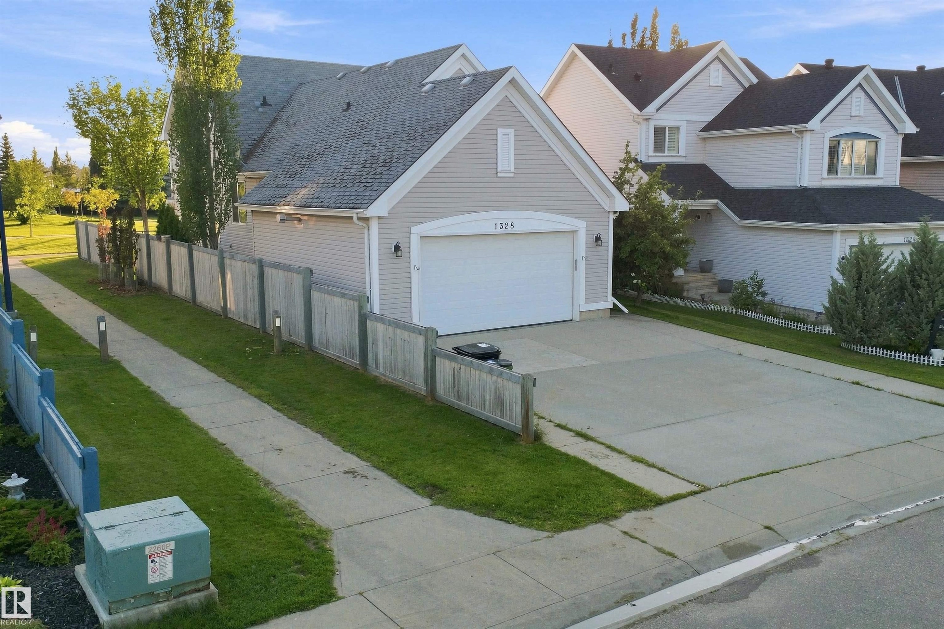 Property exterior featuring light siding, a dark roof, and an attached garage with a white door - 1328 80 Street Sw, Edmonton, AB - Outdoor