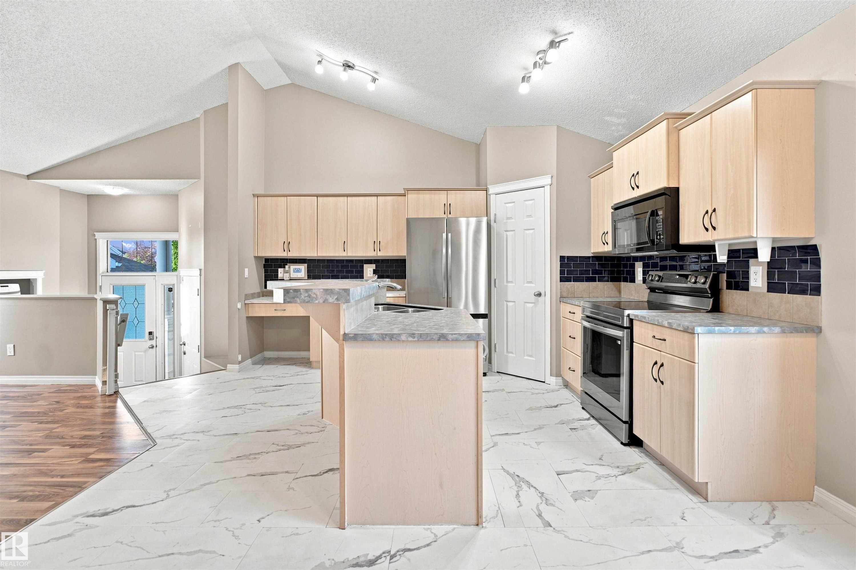 Kitchen featuring light wood-finish cabinetry, black subway tile backsplash, and light-toned countertops - 1328 80 Street Sw, Edmonton, AB - Indoor Photo Showing Kitchen
