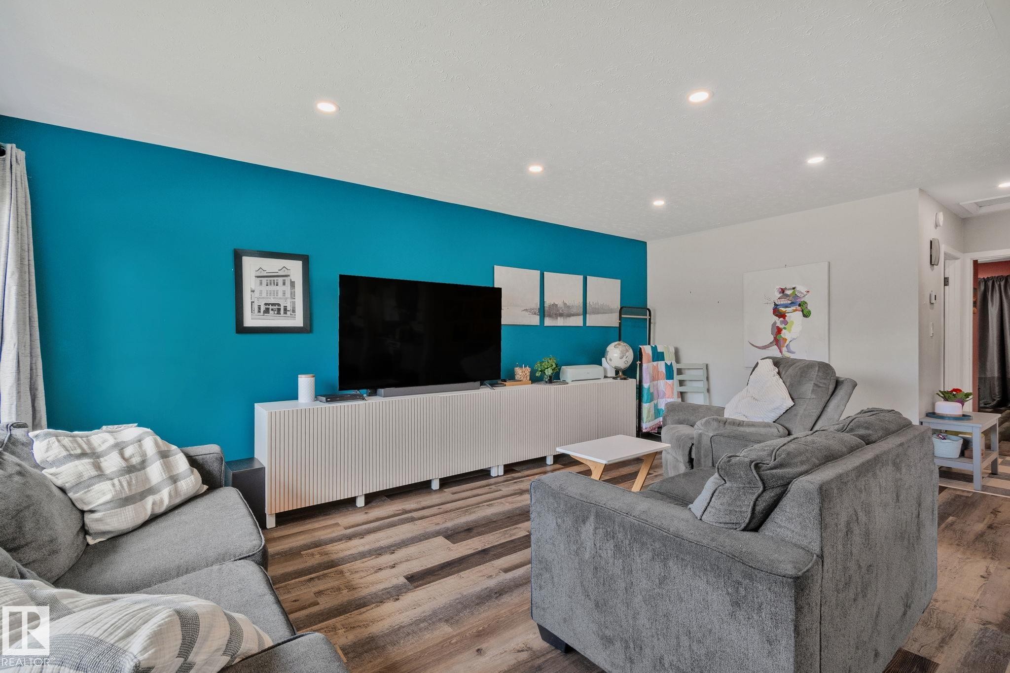 Living area featuring wood-finish flooring, recessed lighting, and a prominent accent wall - 4723 105 Street Nw, Edmonton, AB - Indoor Photo Showing Living Room