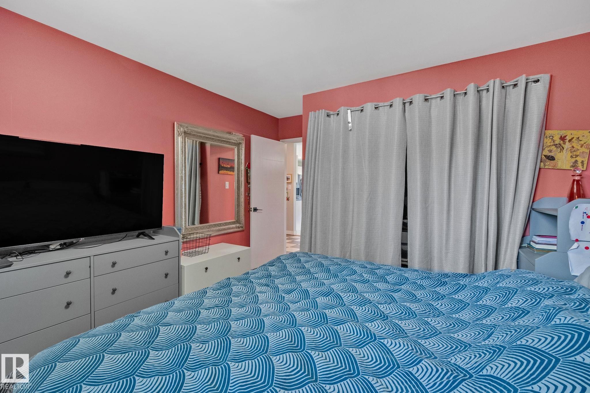 Interior room featuring red-painted walls, a built-in closet with privacy curtains, and a white interior door - 4723 105 Street Nw, Edmonton, AB - Indoor Photo Showing Bedroom