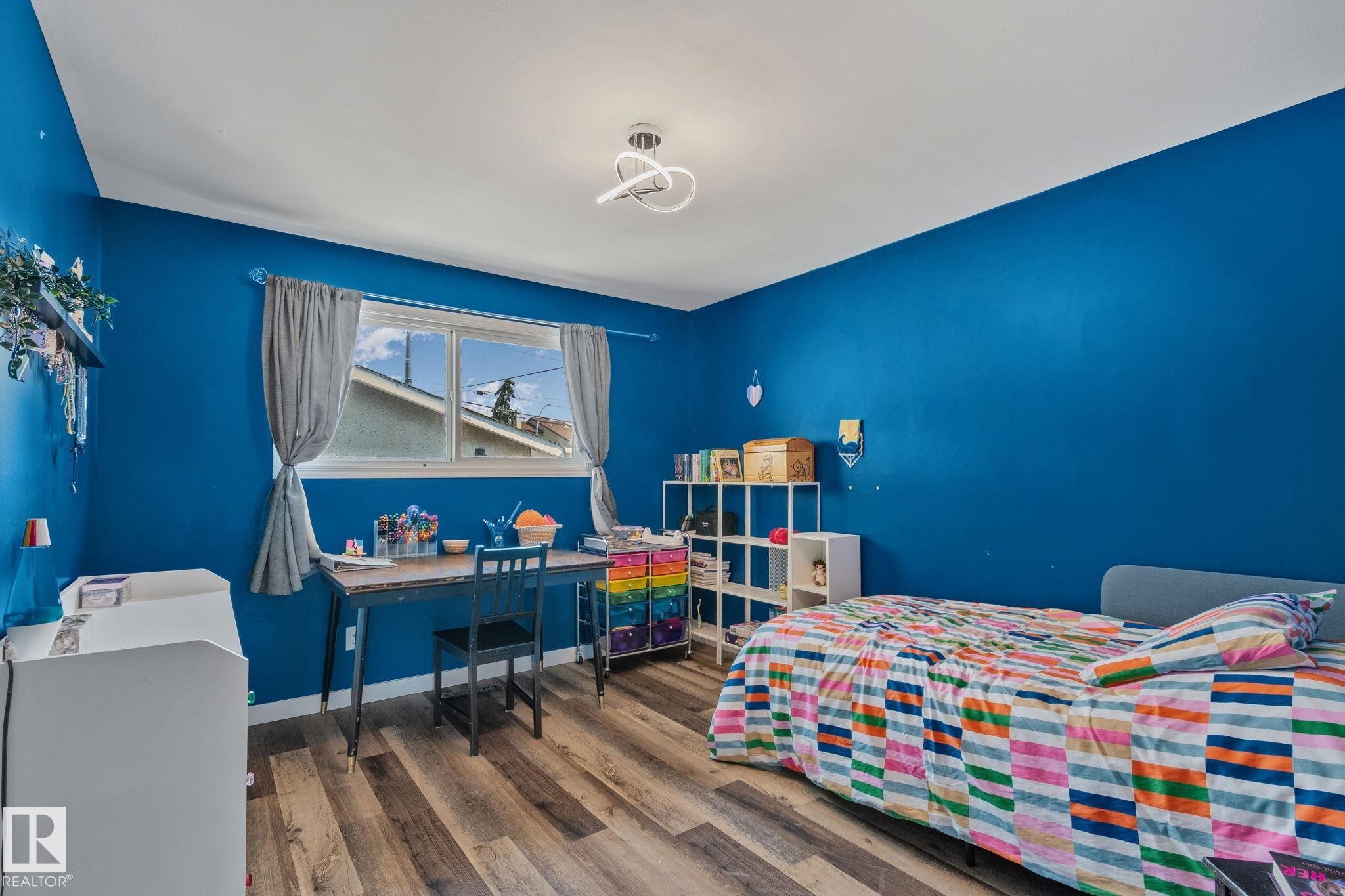 Bright room featuring wood-finish flooring, a double-pane window, and a contemporary ceiling fixture - 4723 105 Street Nw, Edmonton, AB - Indoor Photo Showing Bedroom