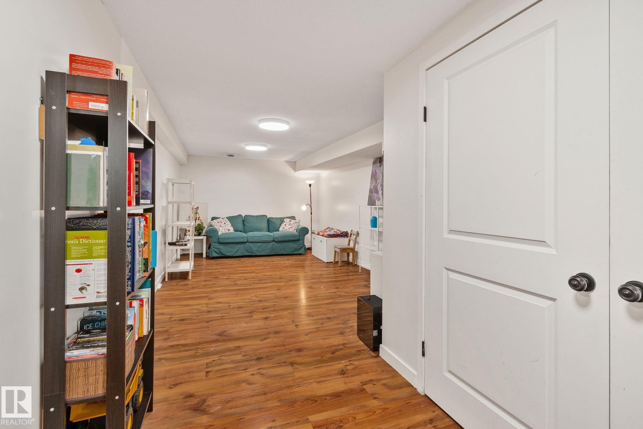 Spacious room featuring wood-finish flooring, recessed lighting, and white panel doors - 4723 105 Street Nw, Edmonton, AB - Indoor Photo Showing Other Room