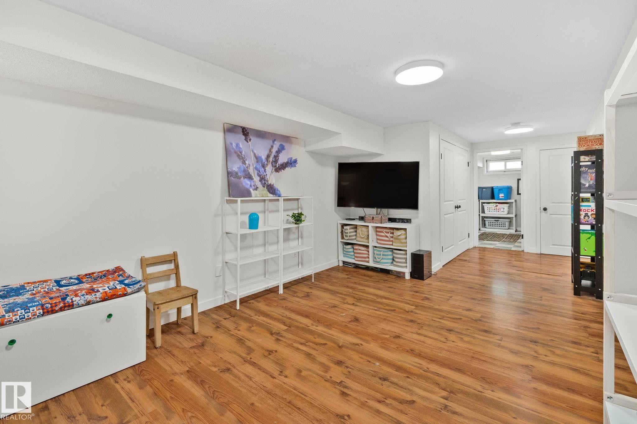 Spacious lower level featuring wood-finish flooring, recessed lighting, and crisp white walls - 4723 105 Street Nw, Edmonton, AB - Indoor Photo Showing Other Room