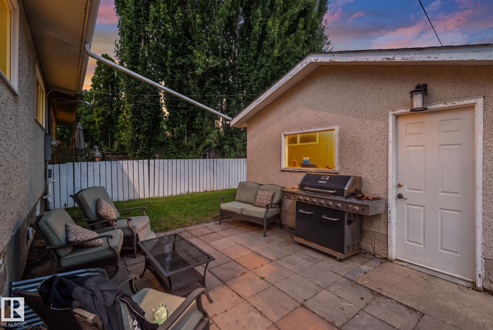 Paver patio with a white picket fence, accented by mature trees - 4723 105 Street Nw, Edmonton, AB - Outdoor With Exterior