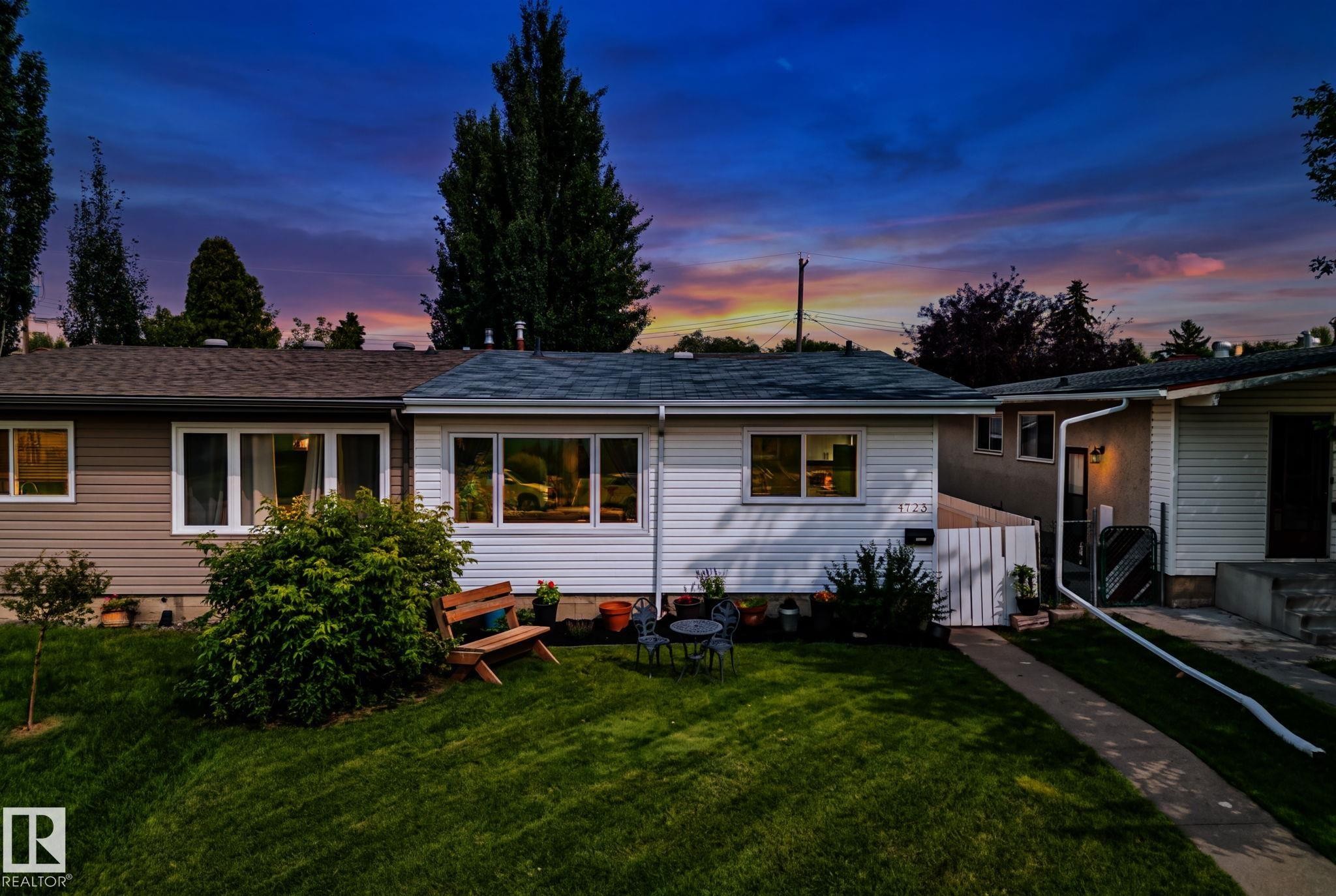 White siding exterior featuring multiple windows, a manicured front lawn, and a concrete walkway - 4723 105 Street Nw, Edmonton, AB - Outdoor