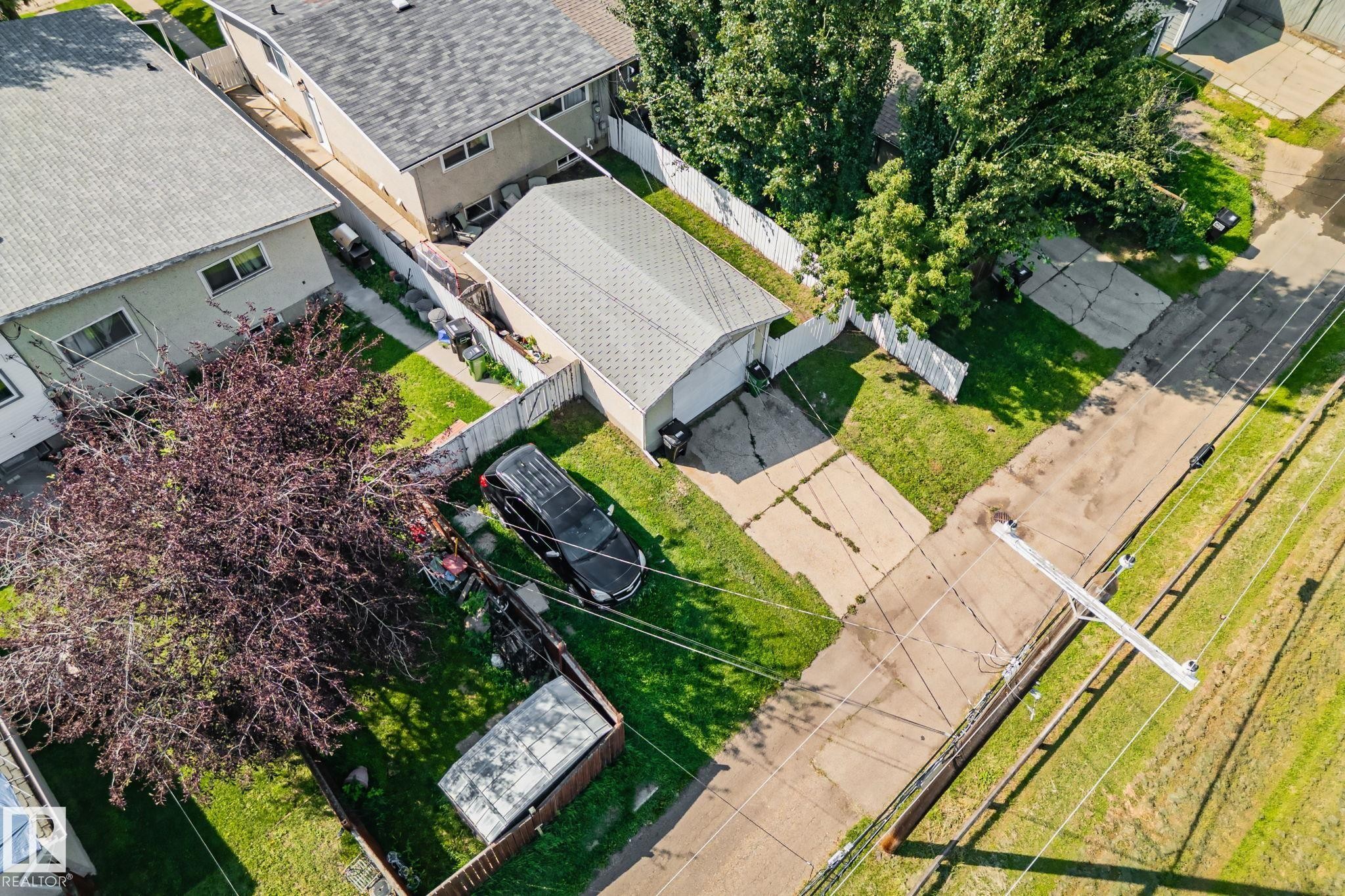 Expansive residential lot featuring a detached garage with a gabled roof, a large mature tree, and green lawn areas - 4723 105 Street Nw, Edmonton, AB - Outdoor With View