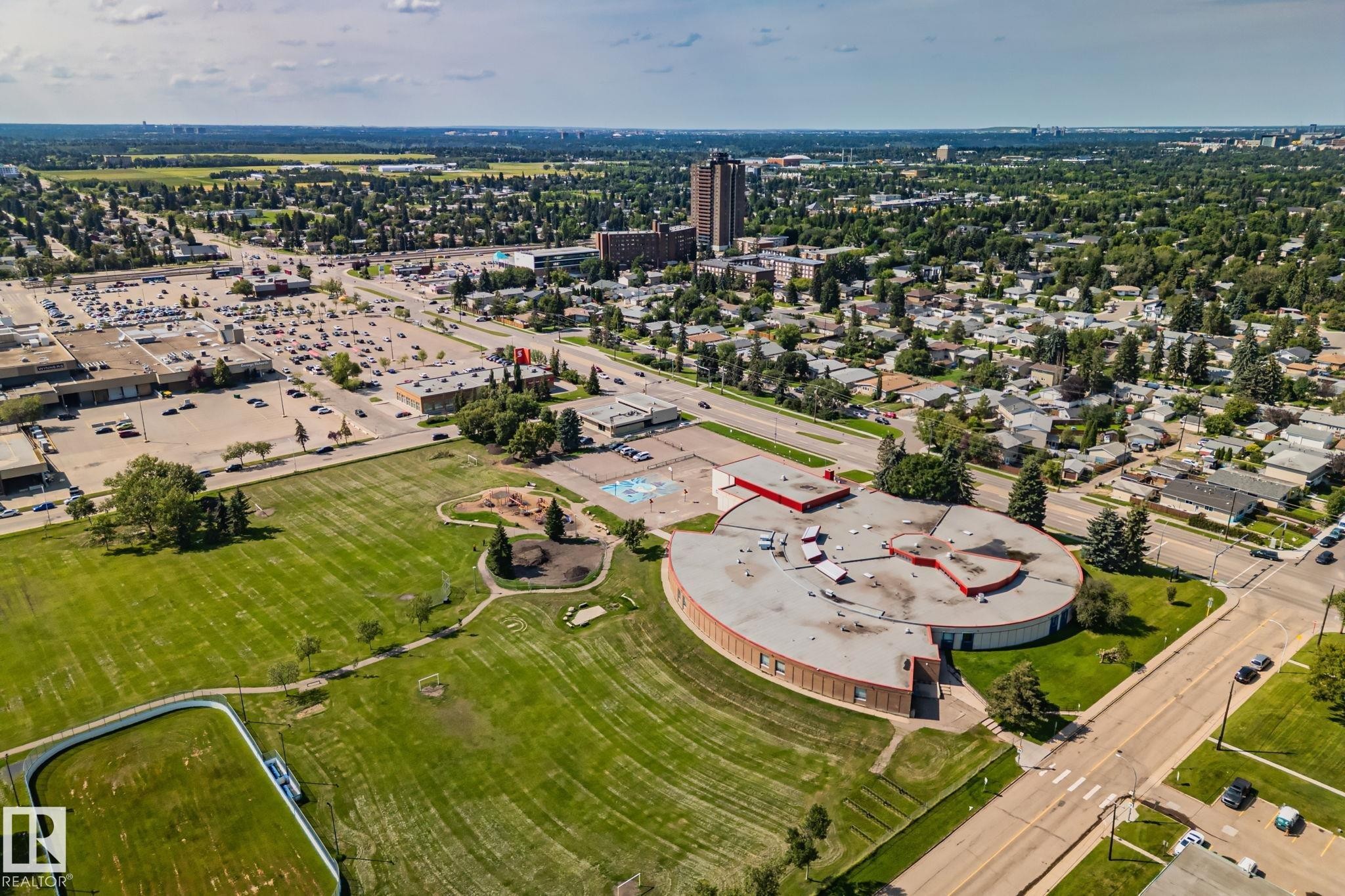Aerial perspective showcasing an expansive green space with a track, surrounded by residential areas and commercial establishments - 4723 105 Street Nw, Edmonton, AB - Outdoor With View