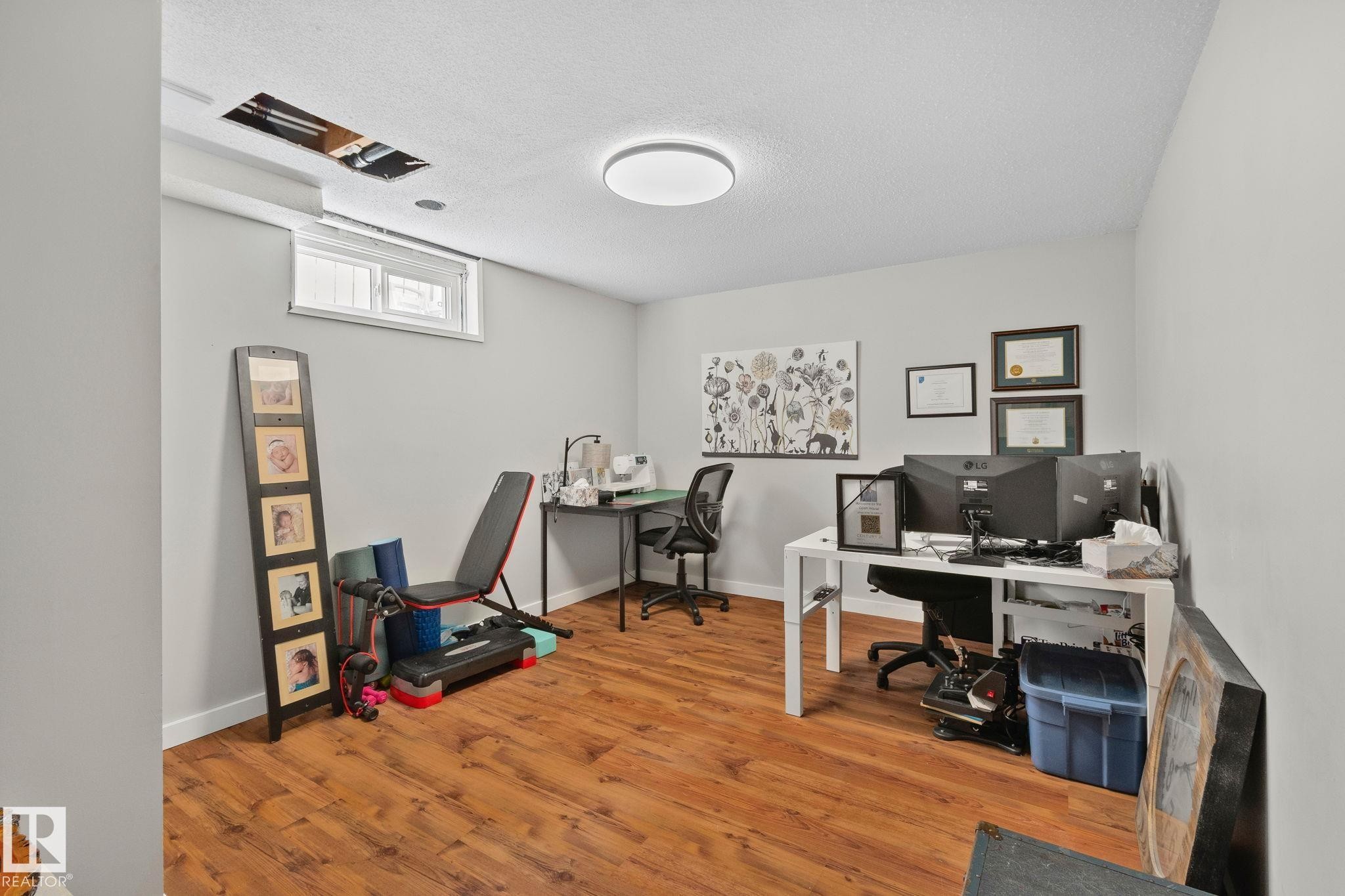 Spacious room featuring wood-finish flooring, light gray walls, and a contemporary flush-mount ceiling light - 4723 105 Street Nw, Edmonton, AB - Indoor Photo Showing Office