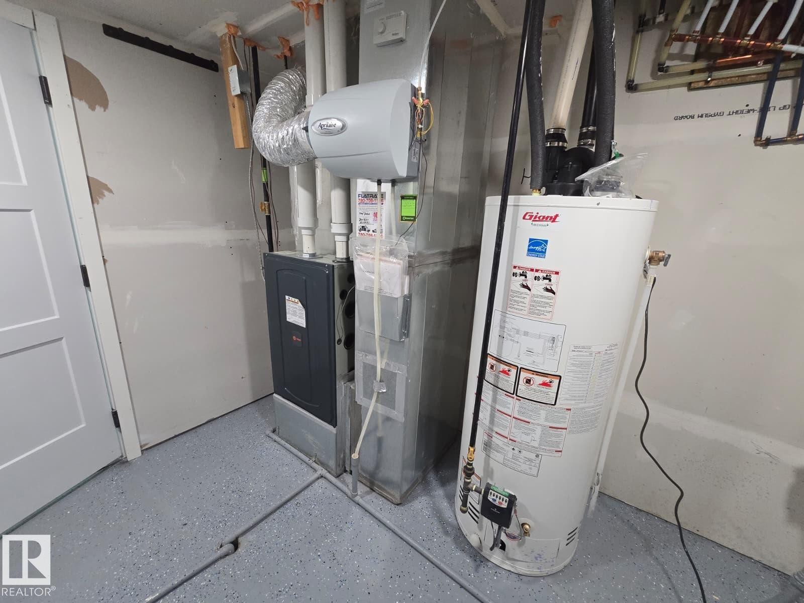 Utility space featuring a water heater, furnace, and a light gray epoxy floor - 228 36 Street Sw, Edmonton, AB - Indoor Photo Showing Basement