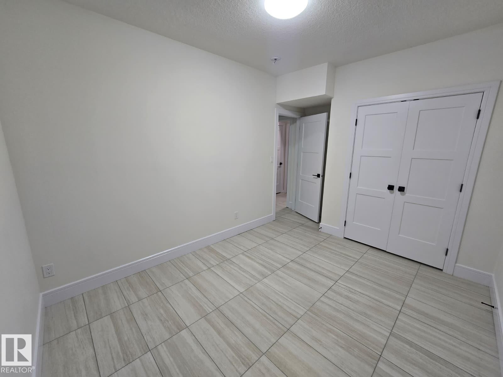 Room featuring light-colored walls and wood-finish tile flooring - 228 36 Street Sw, Edmonton, AB - Indoor Photo Showing Other Room