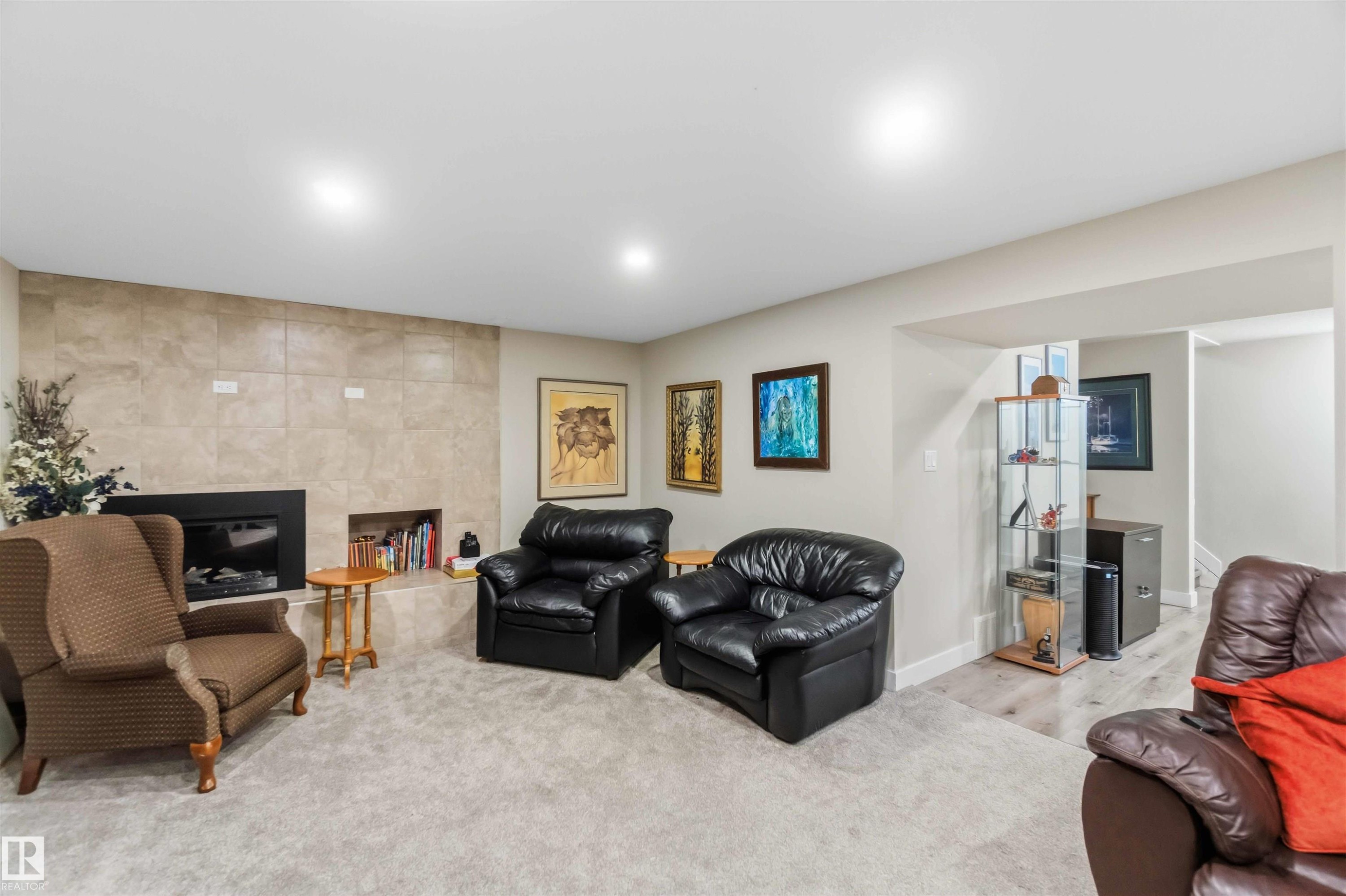 Carpeted living area featuring a tile-surround fireplace with an integrated niche, recessed lighting, light-toned walls, and wood-finish flooring in the background - 11351 35A Avenue Nw, Edmonton, AB - Indoor With Fireplace