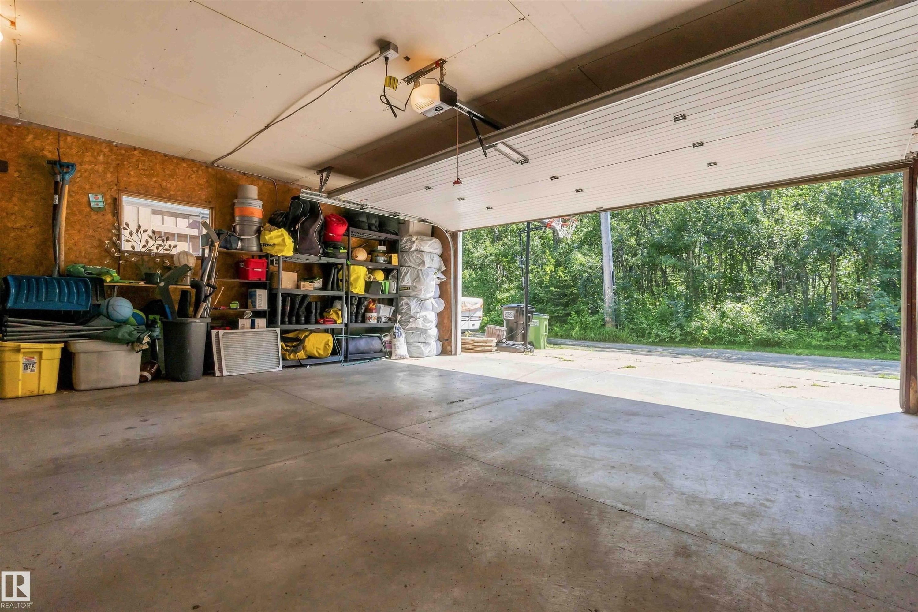 Garage space featuring a concrete floor, exposed wood-finish walls, and an overhead door - 11351 35A Avenue Nw, Edmonton, AB - Indoor Photo Showing Garage