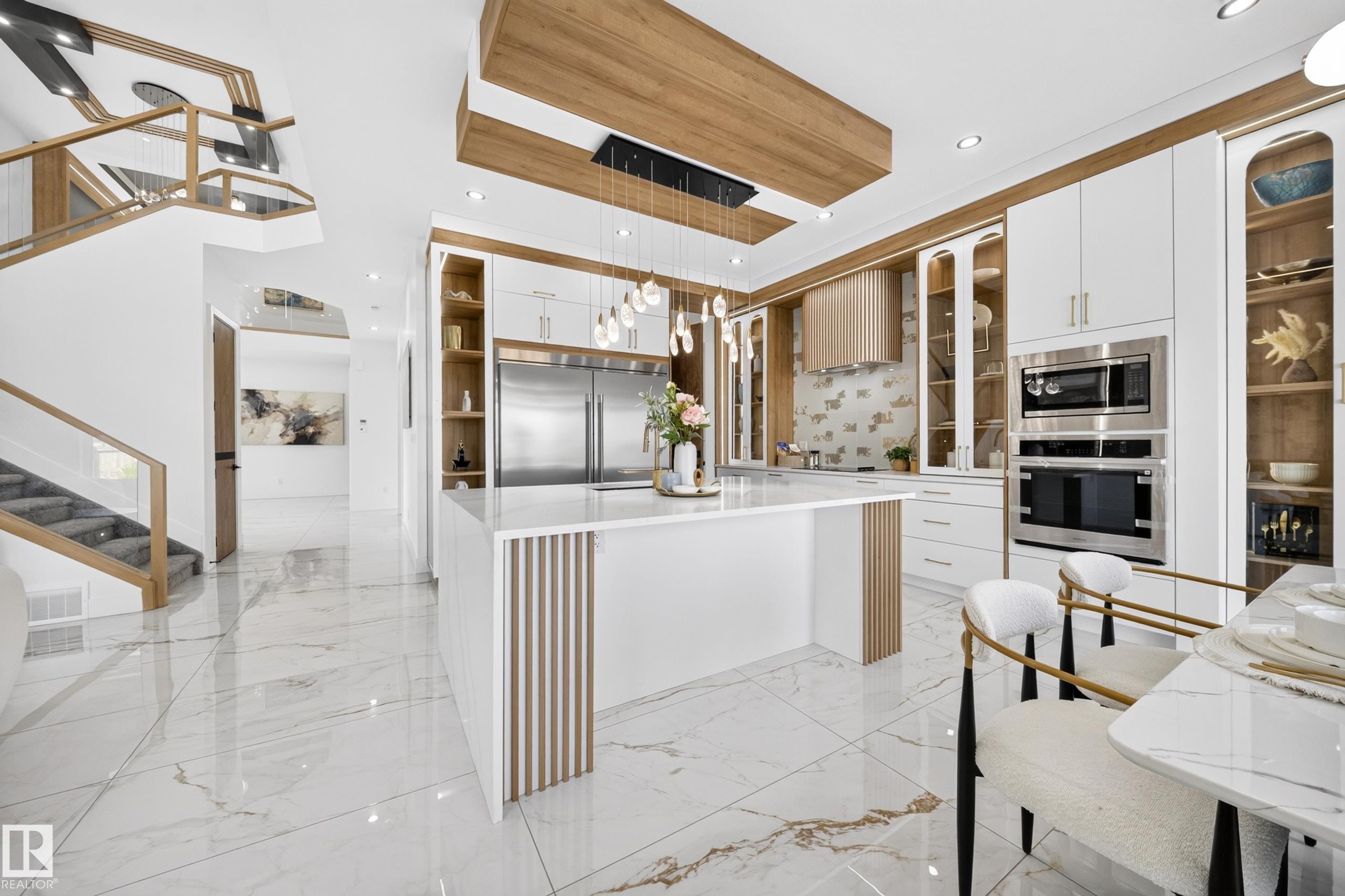 Gourmet kitchen featuring a waterfall island, integrated stainless steel appliances, extensive cabinetry with glass display fronts, recessed lighting, and wood-finish ceiling accents - 423 Robinson Bv, Leduc, AB - Indoor Photo Showing Kitchen