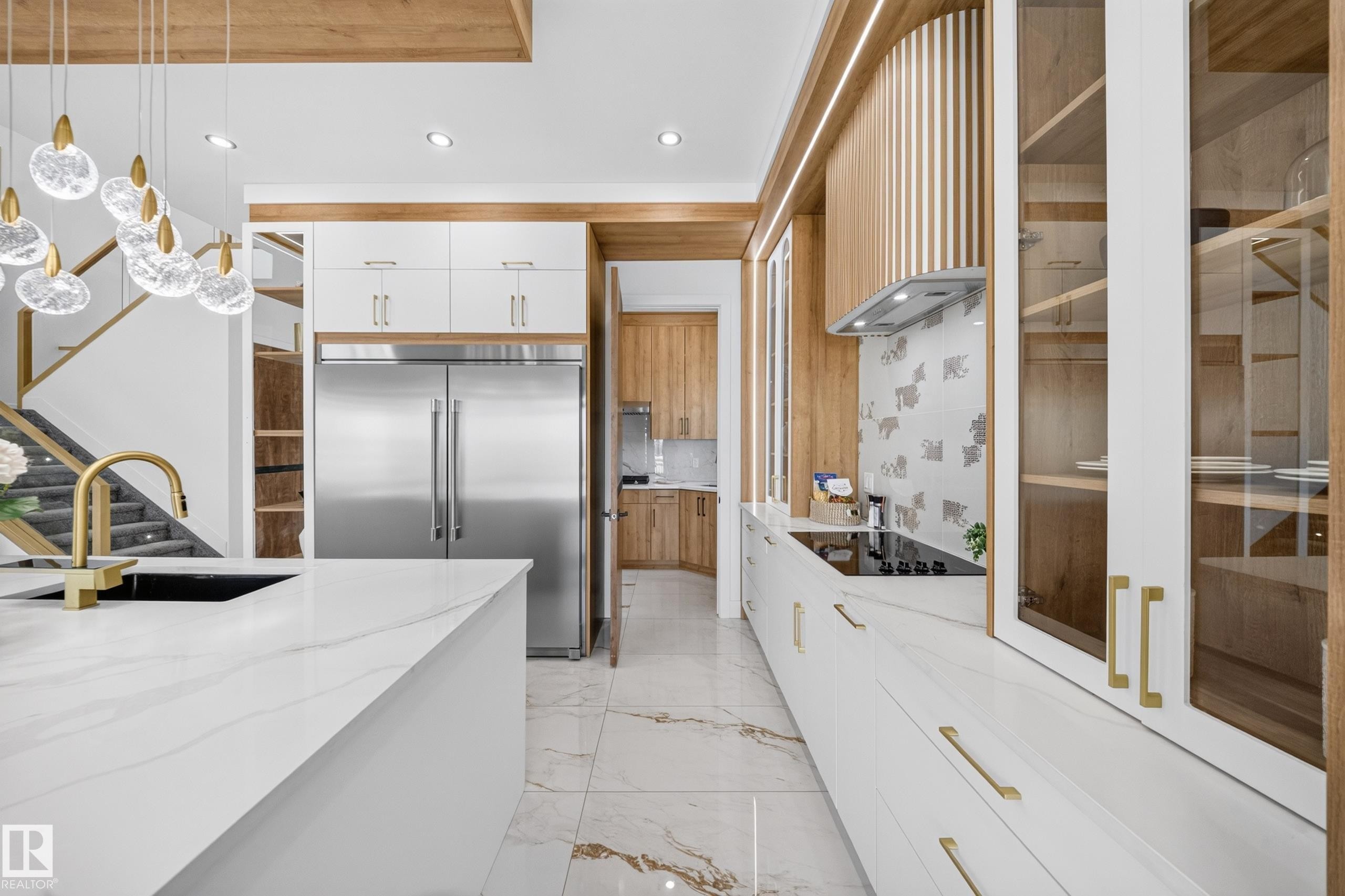 Contemporary kitchen featuring white cabinetry with brass hardware, a large island with a black undermount sink and brass faucet, and integrated stainless steel appliances - 423 Robinson Bv, Leduc, AB - Indoor Photo Showing Kitchen With Upgraded Kitchen