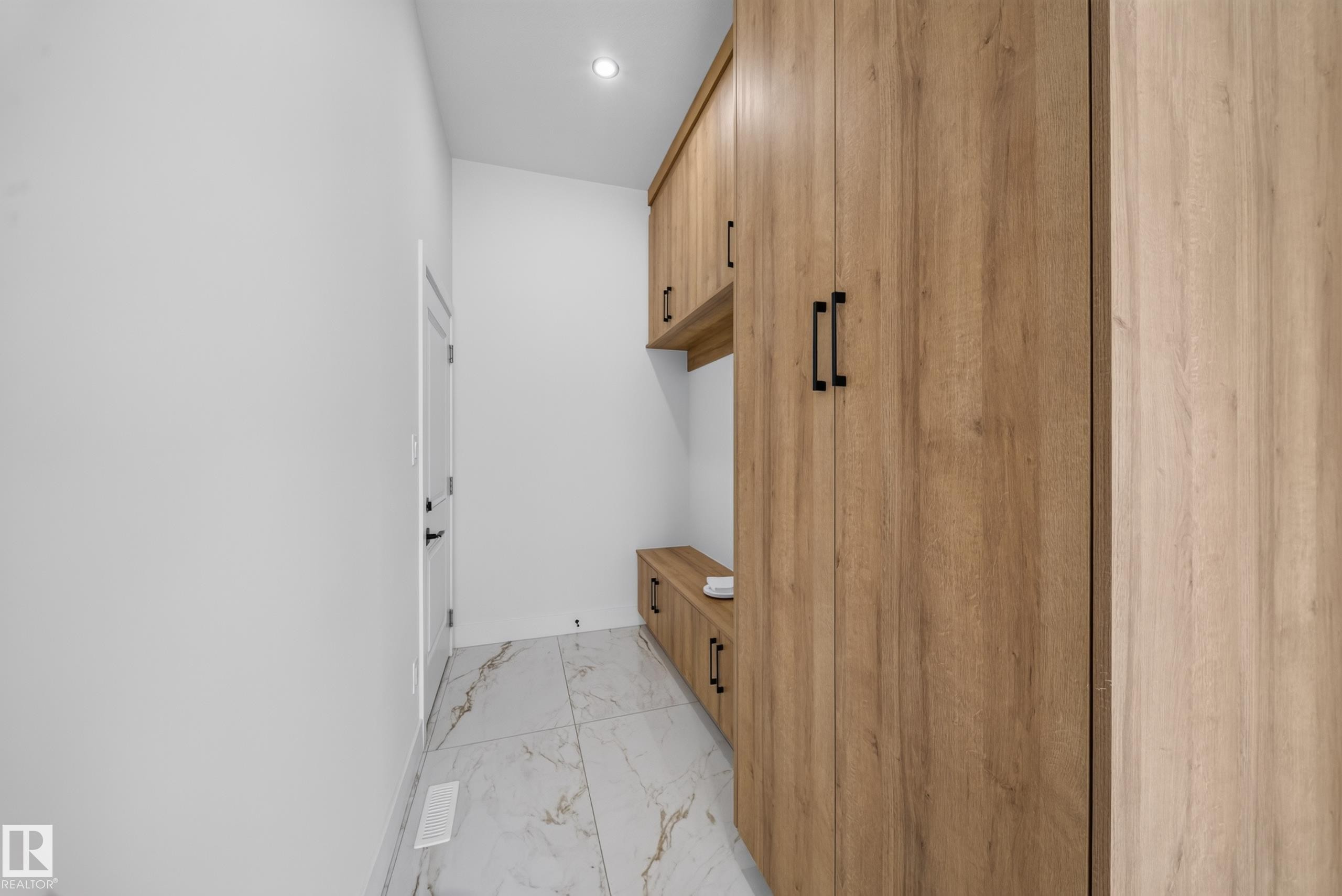 Entryway mudroom with light wood-finish cabinetry, built-in bench, and white large-format tile flooring - 423 Robinson Bv, Leduc, AB - Indoor Photo Showing Other Room