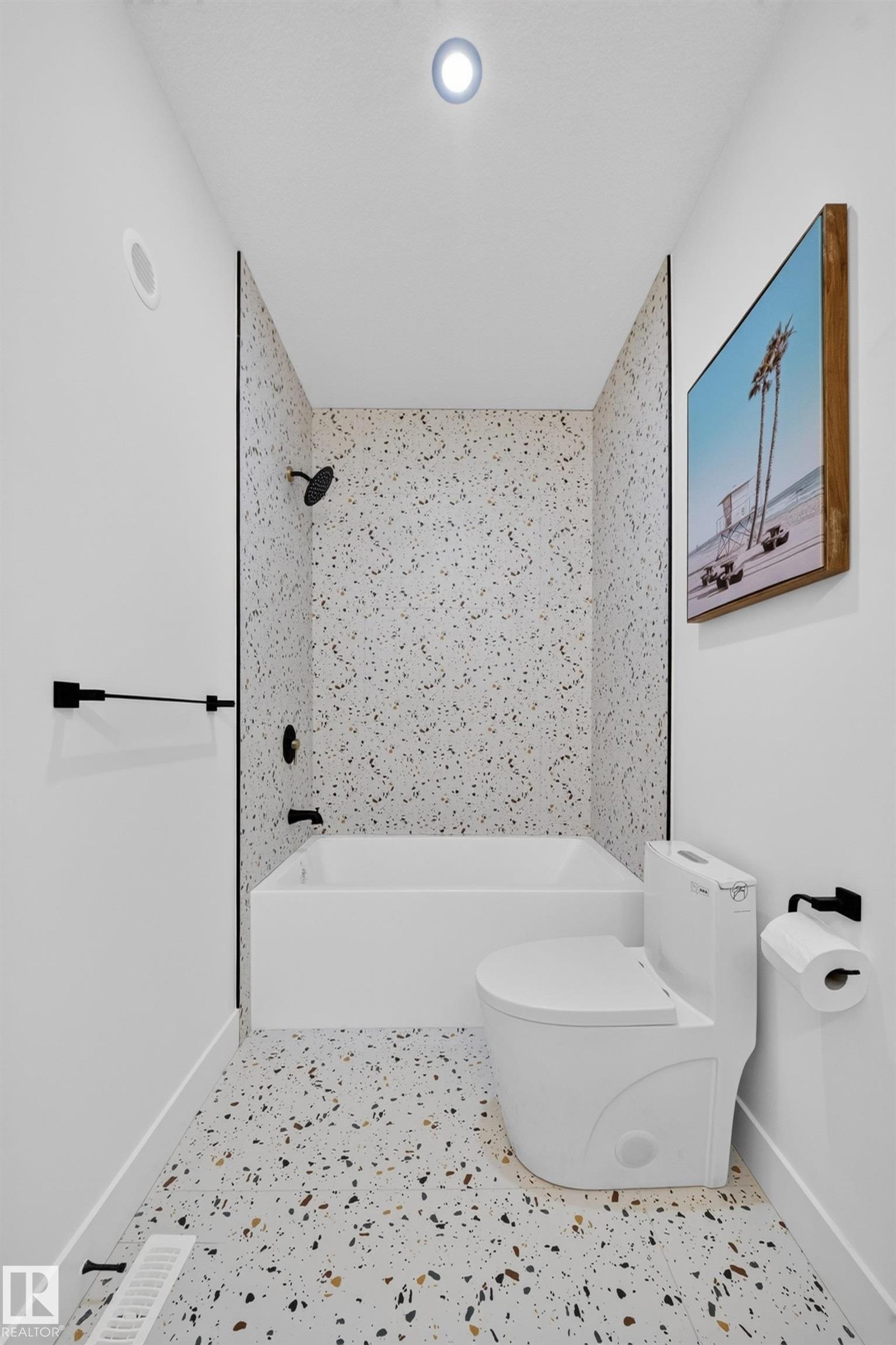 Bathroom featuring a white bathtub, black shower fixtures, a toilet, and patterned terrazzo-style flooring - 423 Robinson Bv, Leduc, AB - Indoor Photo Showing Bathroom