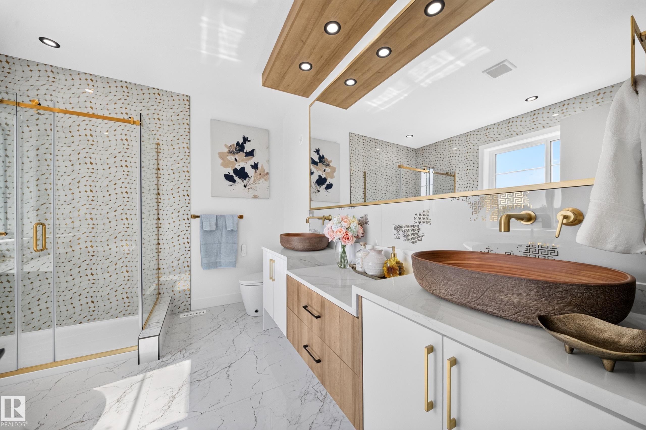 Modern bathroom featuring a dual vanity with unique vessel sinks, a spacious shower with gold-accented glass enclosure, and contemporary wall-mounted faucets - 423 Robinson Bv, Leduc, AB - Indoor