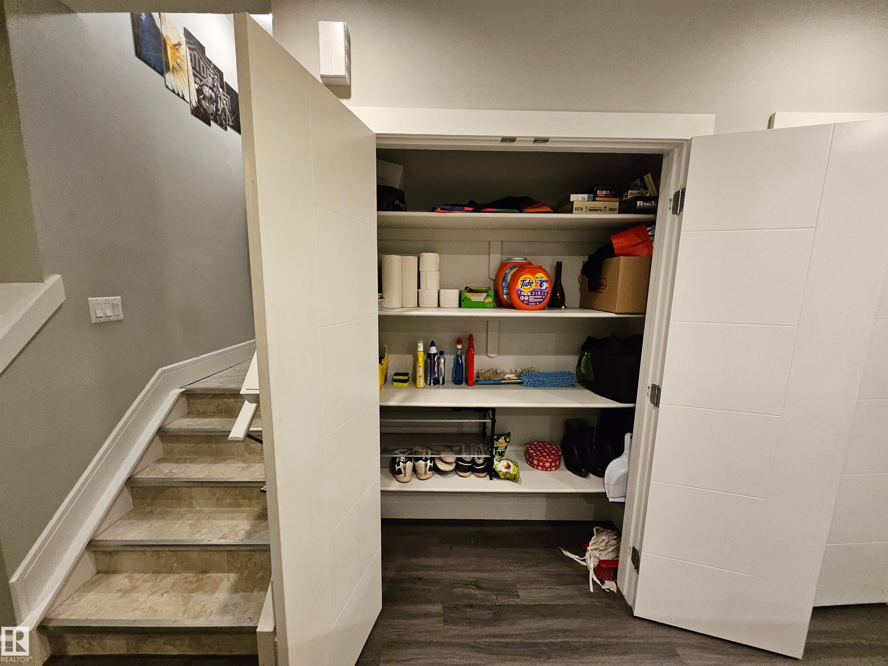 Built-in storage closet featuring white shelving and white paneled doors - 9311 66 Avenue Nw, Edmonton, AB - Indoor
