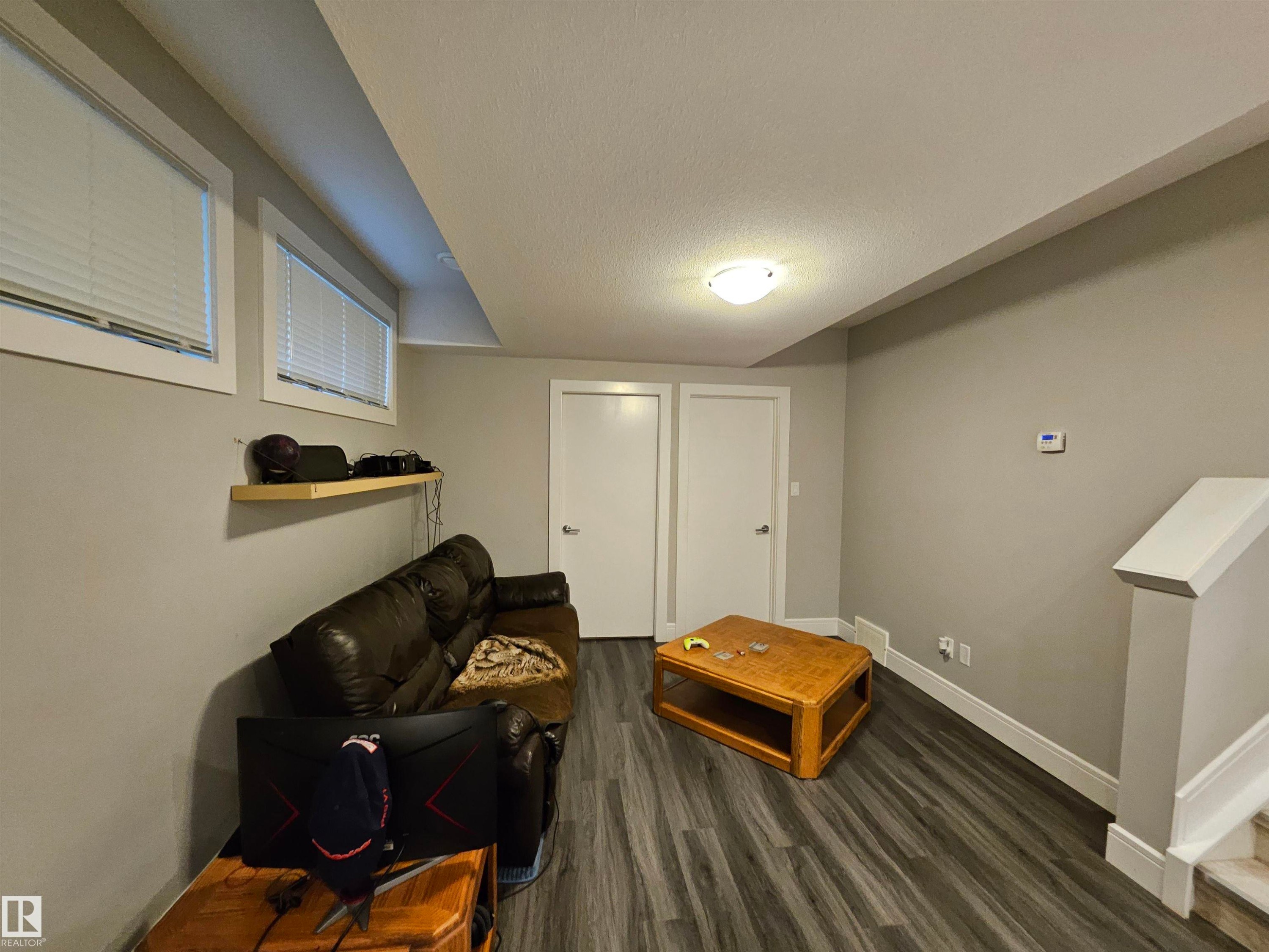 Finished living space featuring wood-finish flooring, light grey walls, and white trim - 9311 66 Avenue Nw, Edmonton, AB - Indoor Photo Showing Other Room