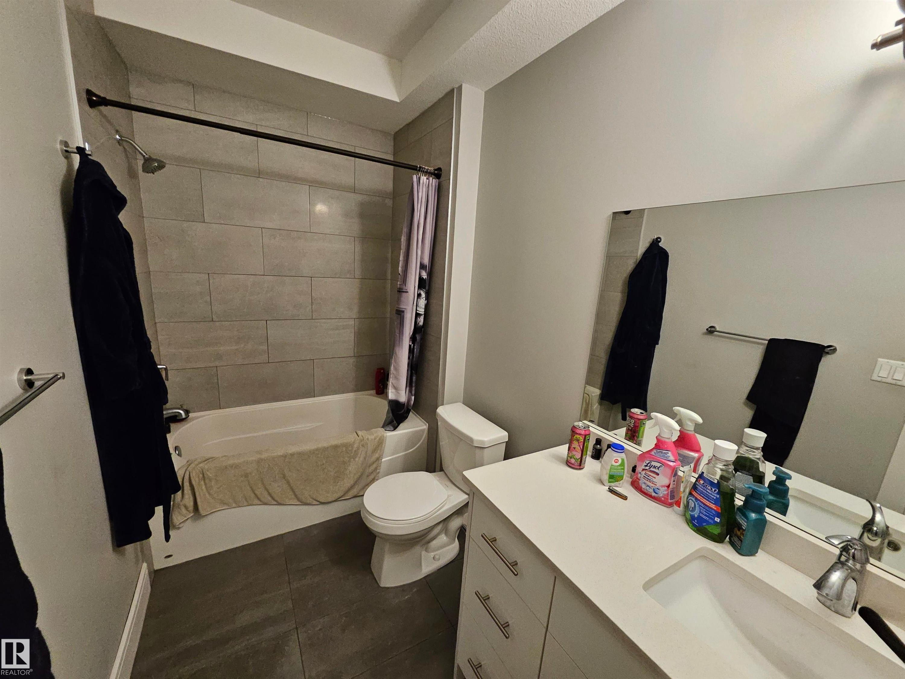 Full bathroom featuring a white tub, light gray subway-tiled shower surround, dark gray large-format floor tiles, a white vanity with an integrated sink, and a large wall-mounted mirror - 9311 66 Avenue Nw, Edmonton, AB - Indoor Photo Showing Bathroom